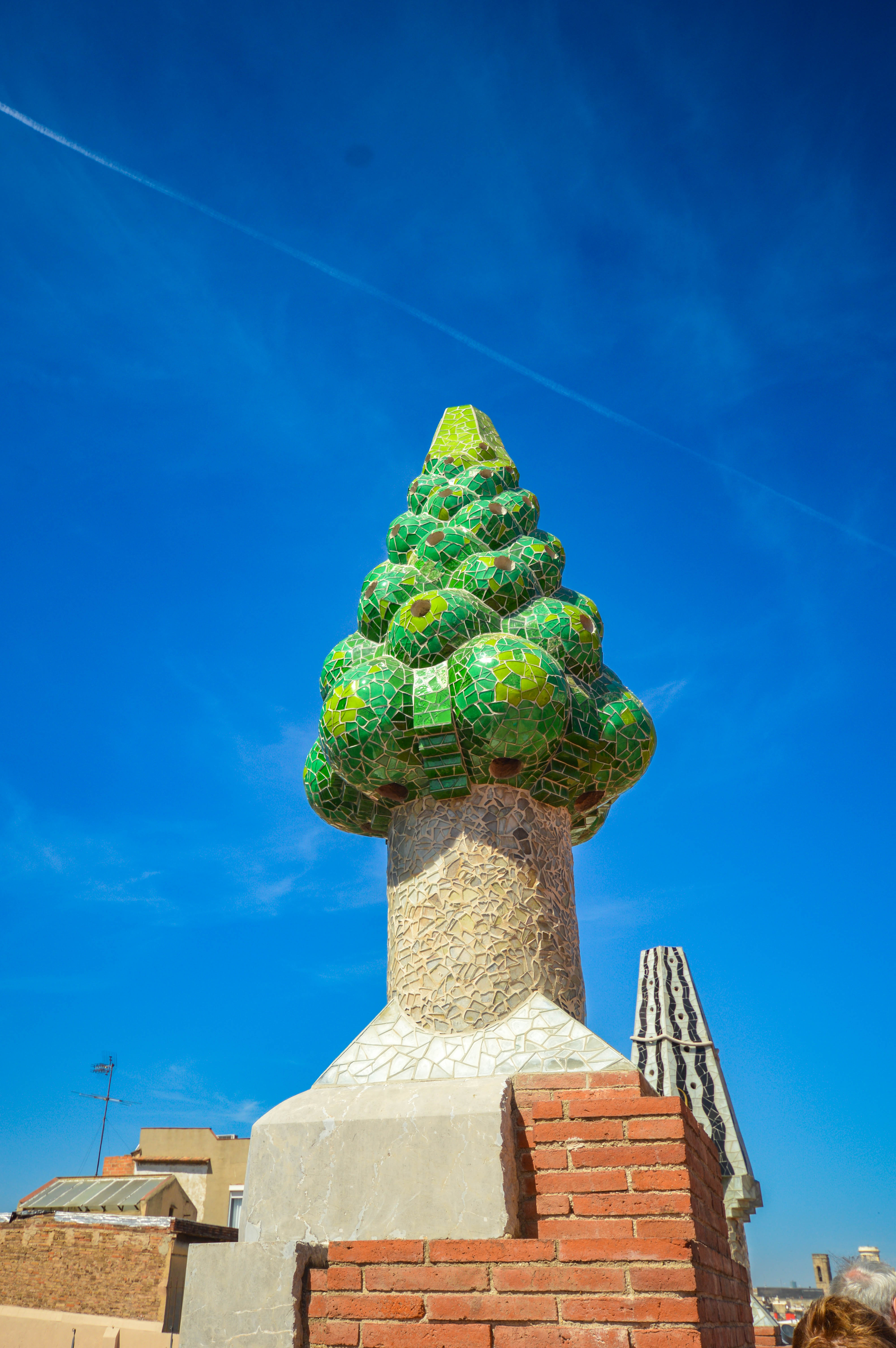 chimney-like base adorned with mosaic tiles in various shades of green and white