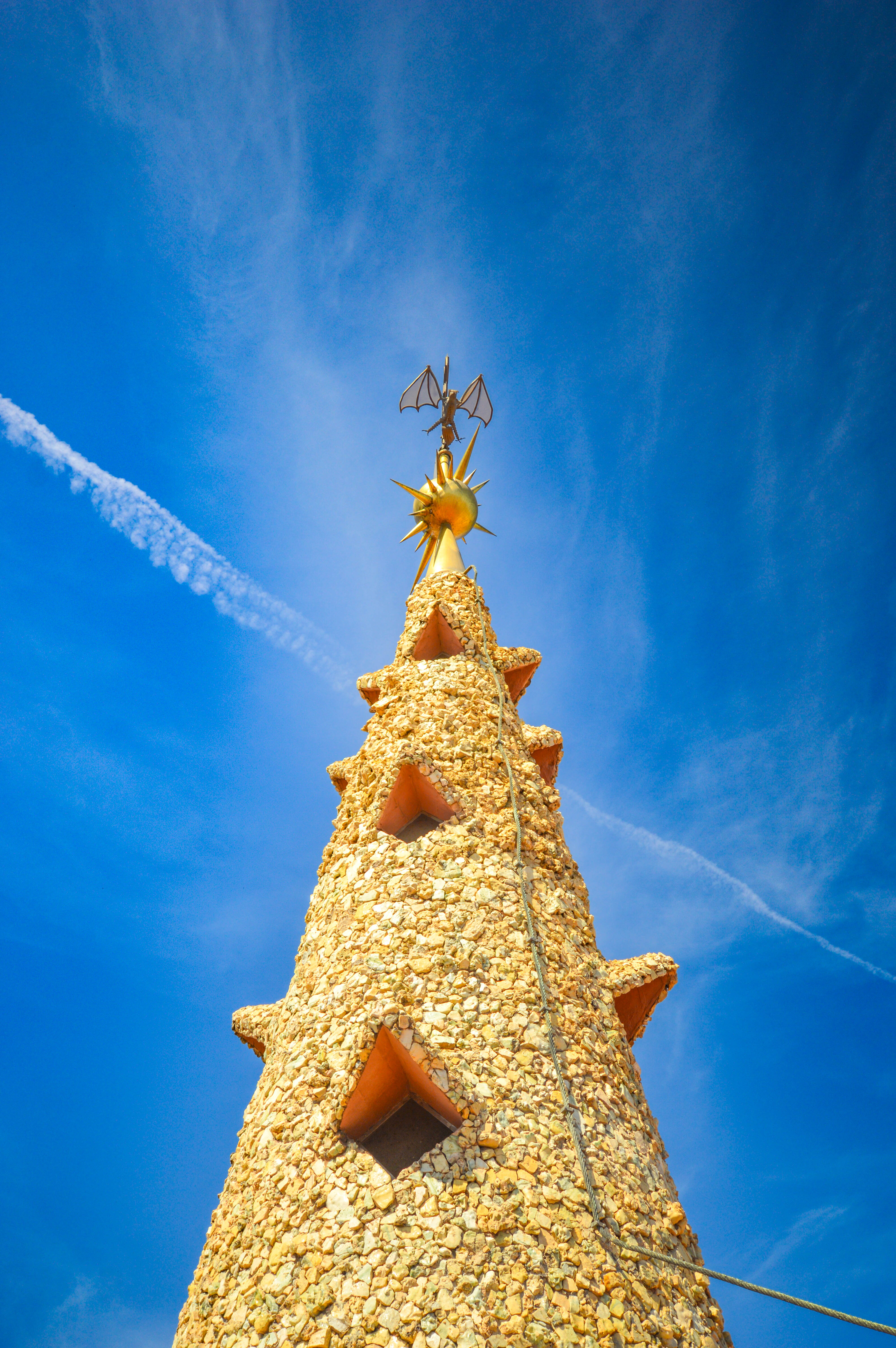 The top of the structure is adorned with a golden, sun-like ornament, which is crowned by a bat-like figure