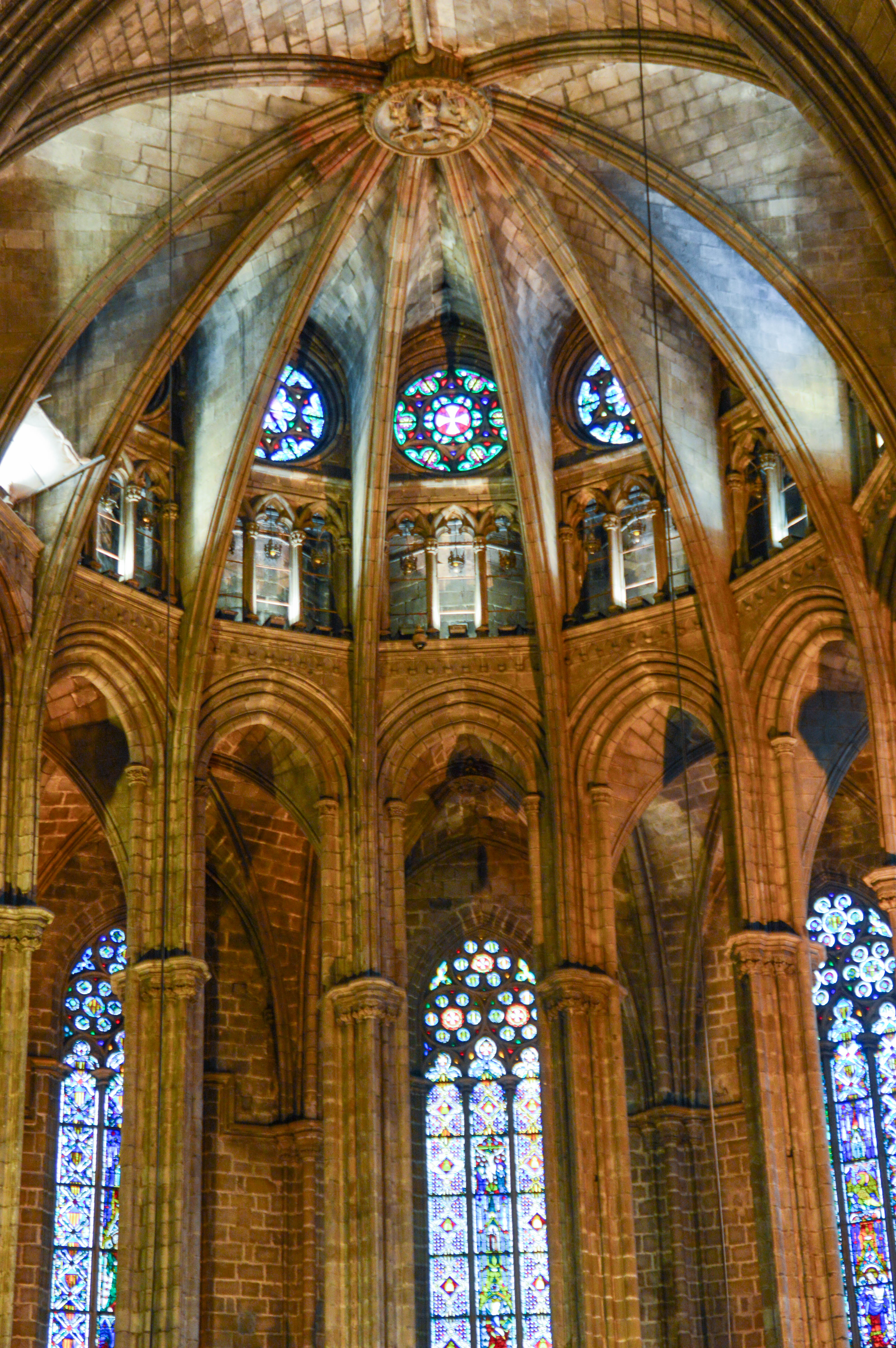 The image depicts the intricate interior of a Gothic-style cathedral, featuring tall, arched ceilings, detailed stonework, and vibrant stained glass windows that allow colorful light to filter into the space.