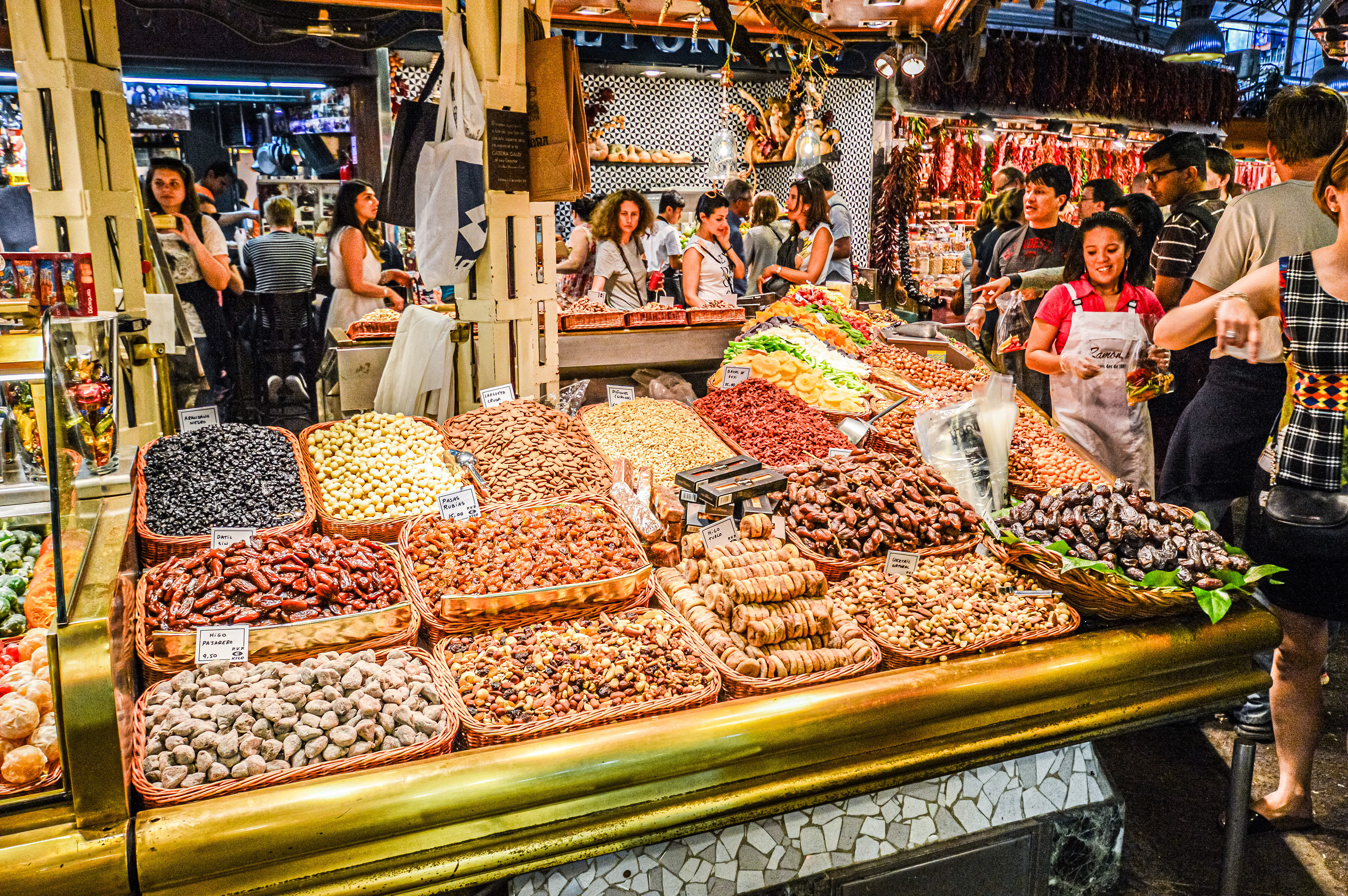 a variety of nuts and dried fruits displayed in baskets on a counter