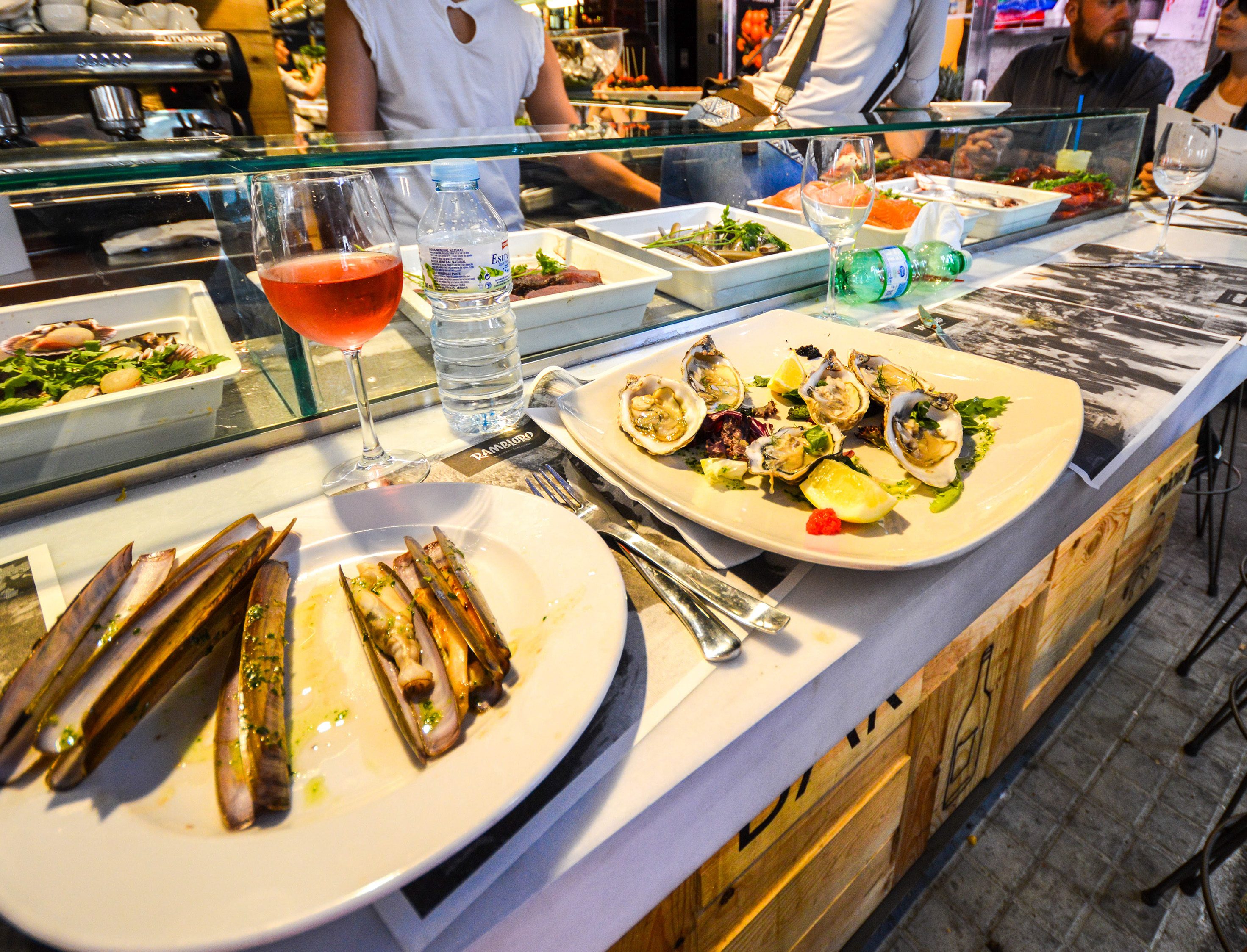 a plate of razor clam, a plate of oysters with garnishes like lemon and herbs