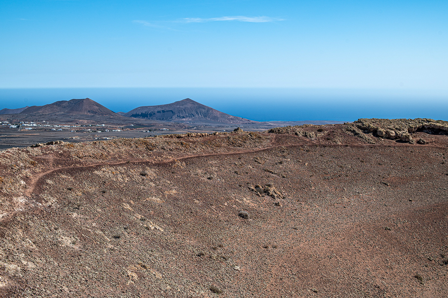 The horizon is marked by the ocean, creating a stark contrast between the arid land and the vast, calm se