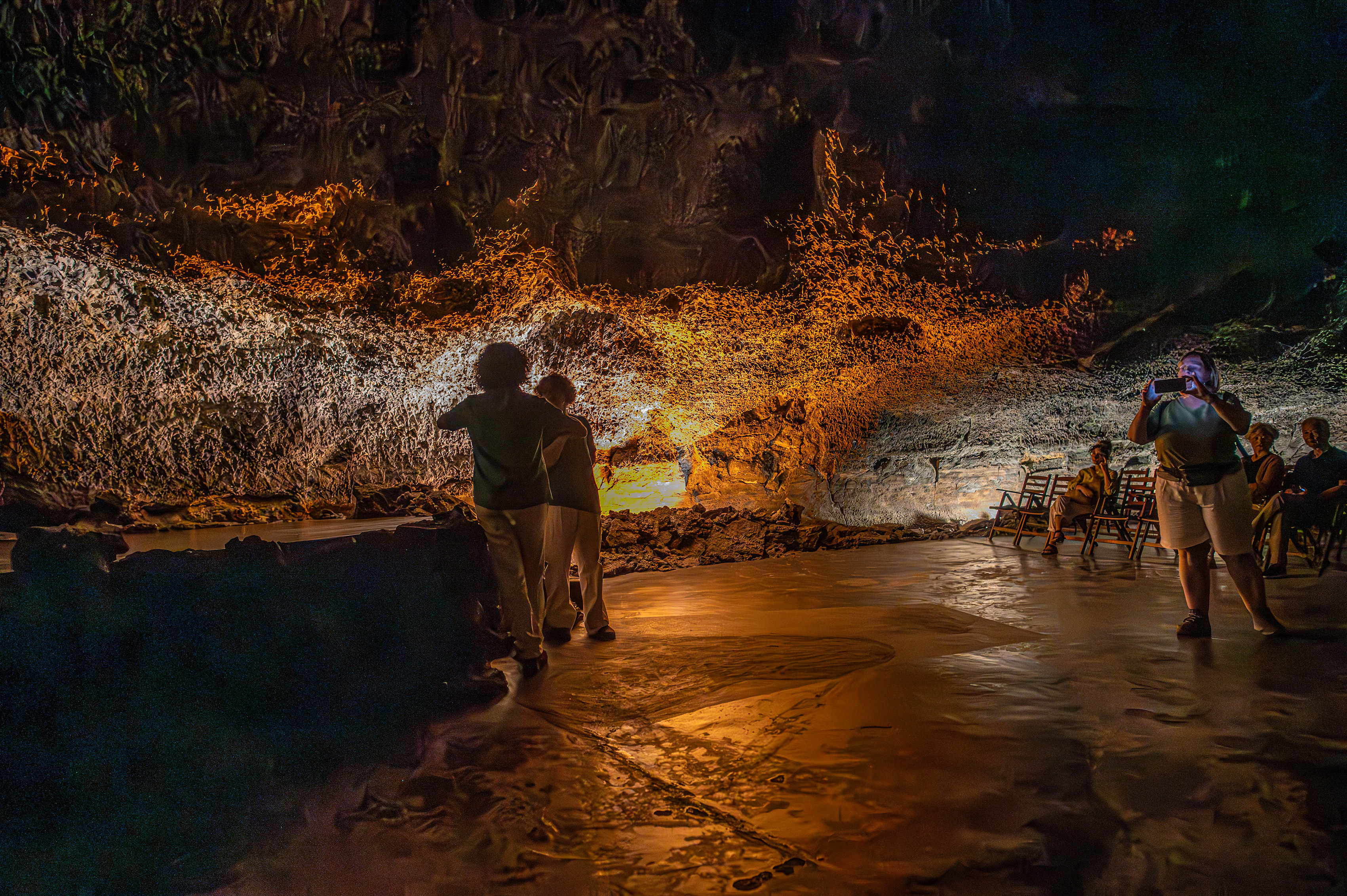 Some individuals are standing and observing the surroundings, while others are seated on benches. One person is taking a photograph.