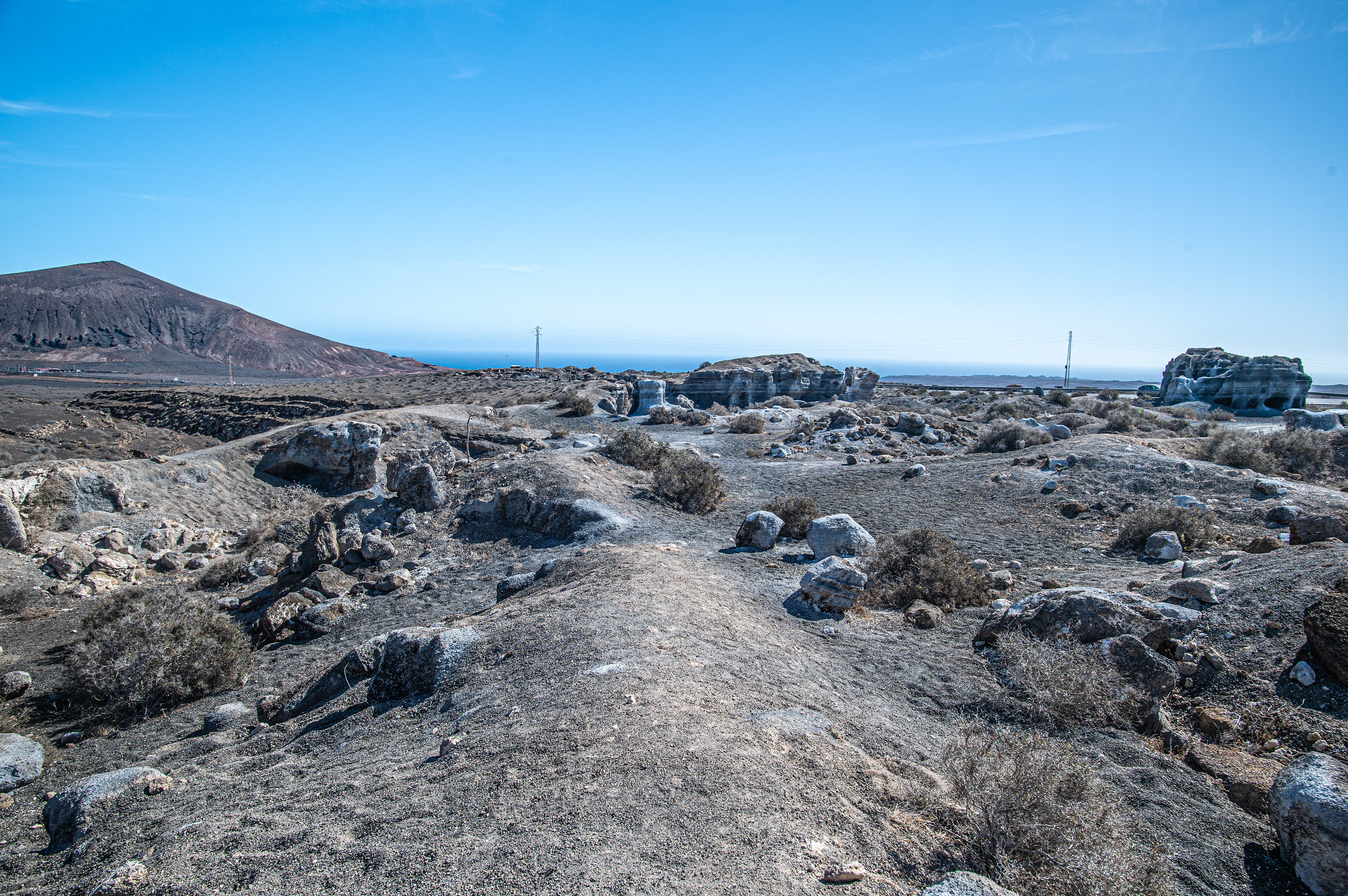 a rocky, barren landscape with scattered vegetation under a clear blue sky