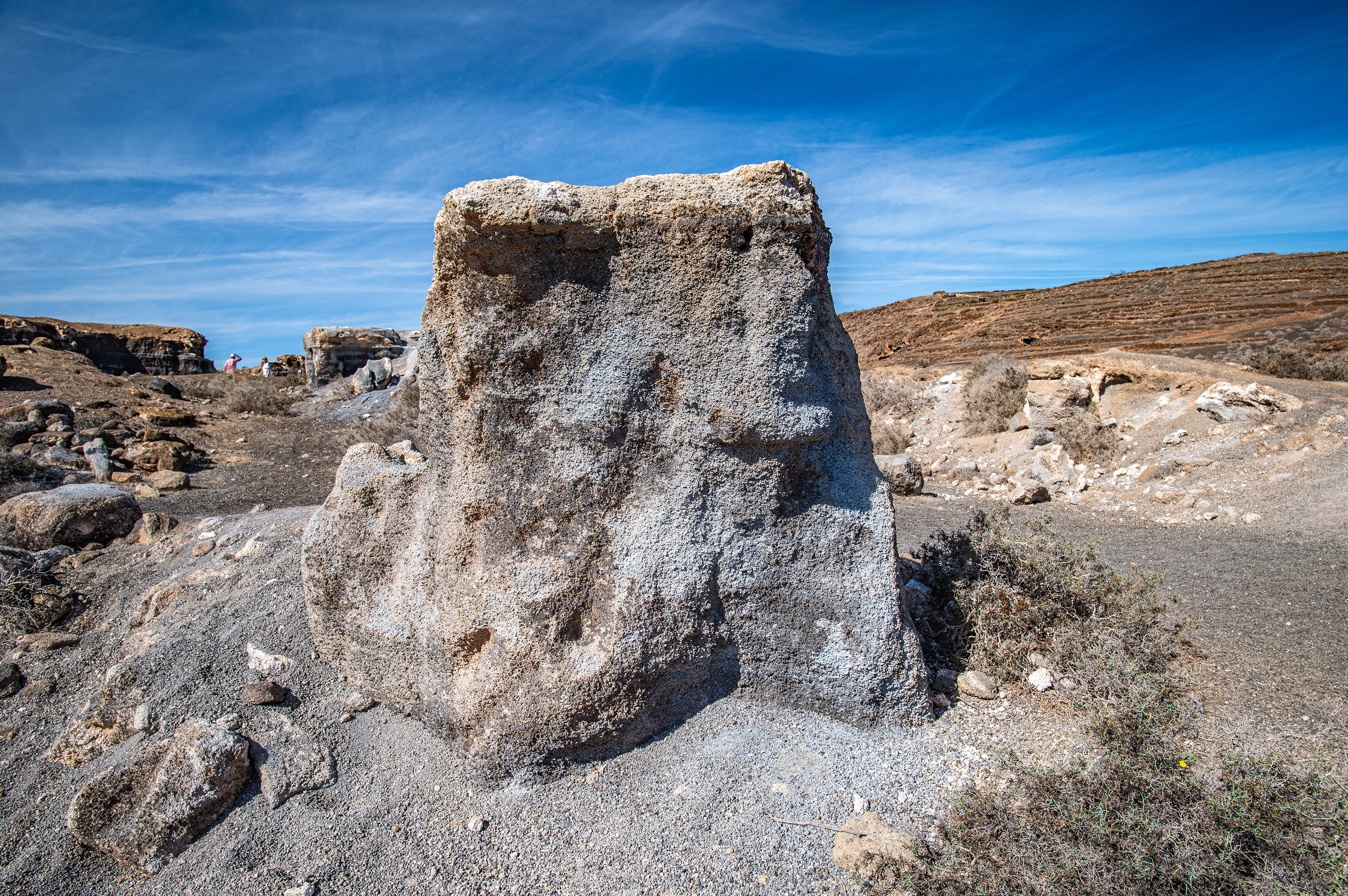 a large, weathered rock formation in a rocky, arid landscape
