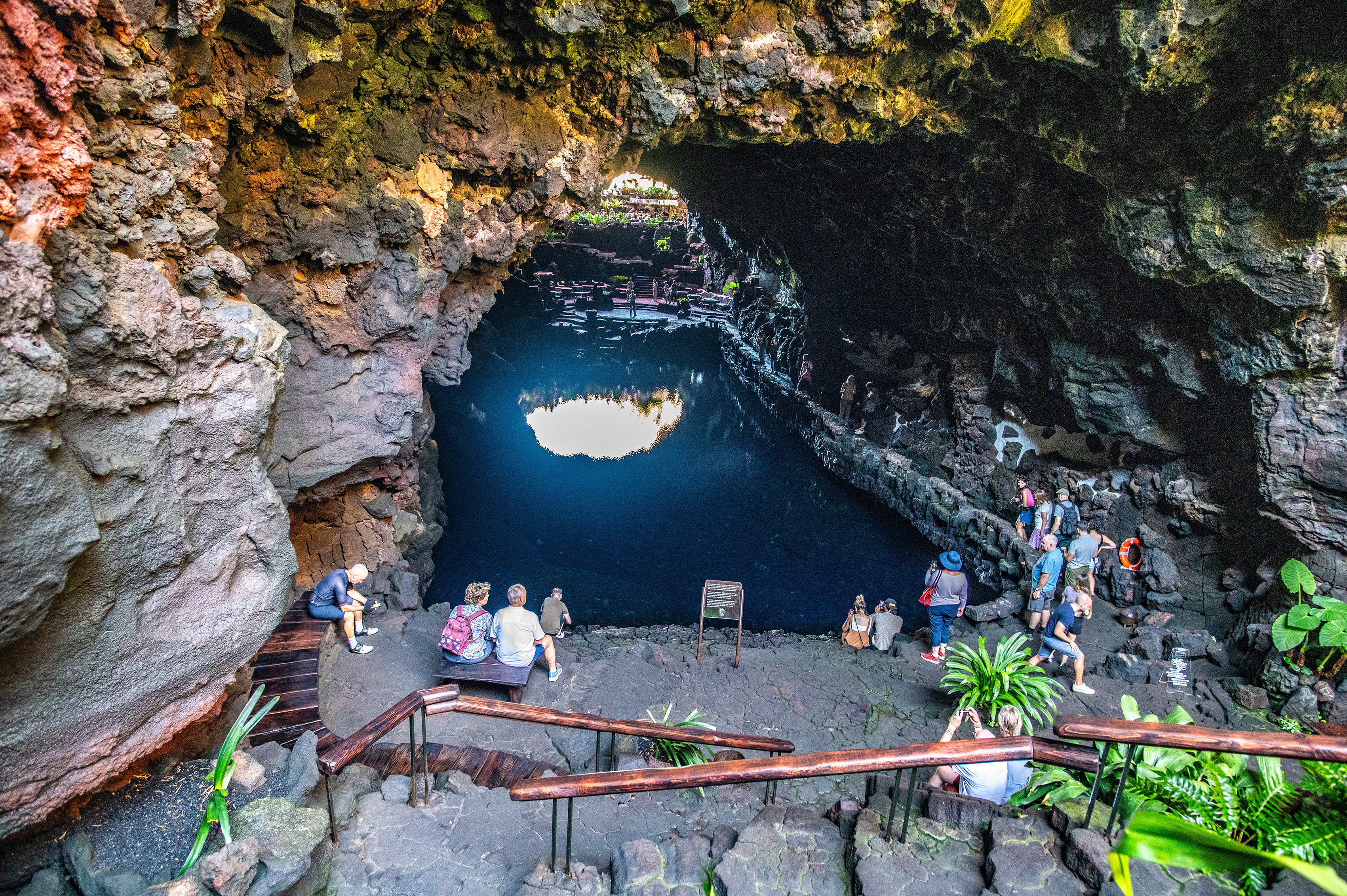 a natural volcanic cave with a deep, circular opening that reveals a body of water below