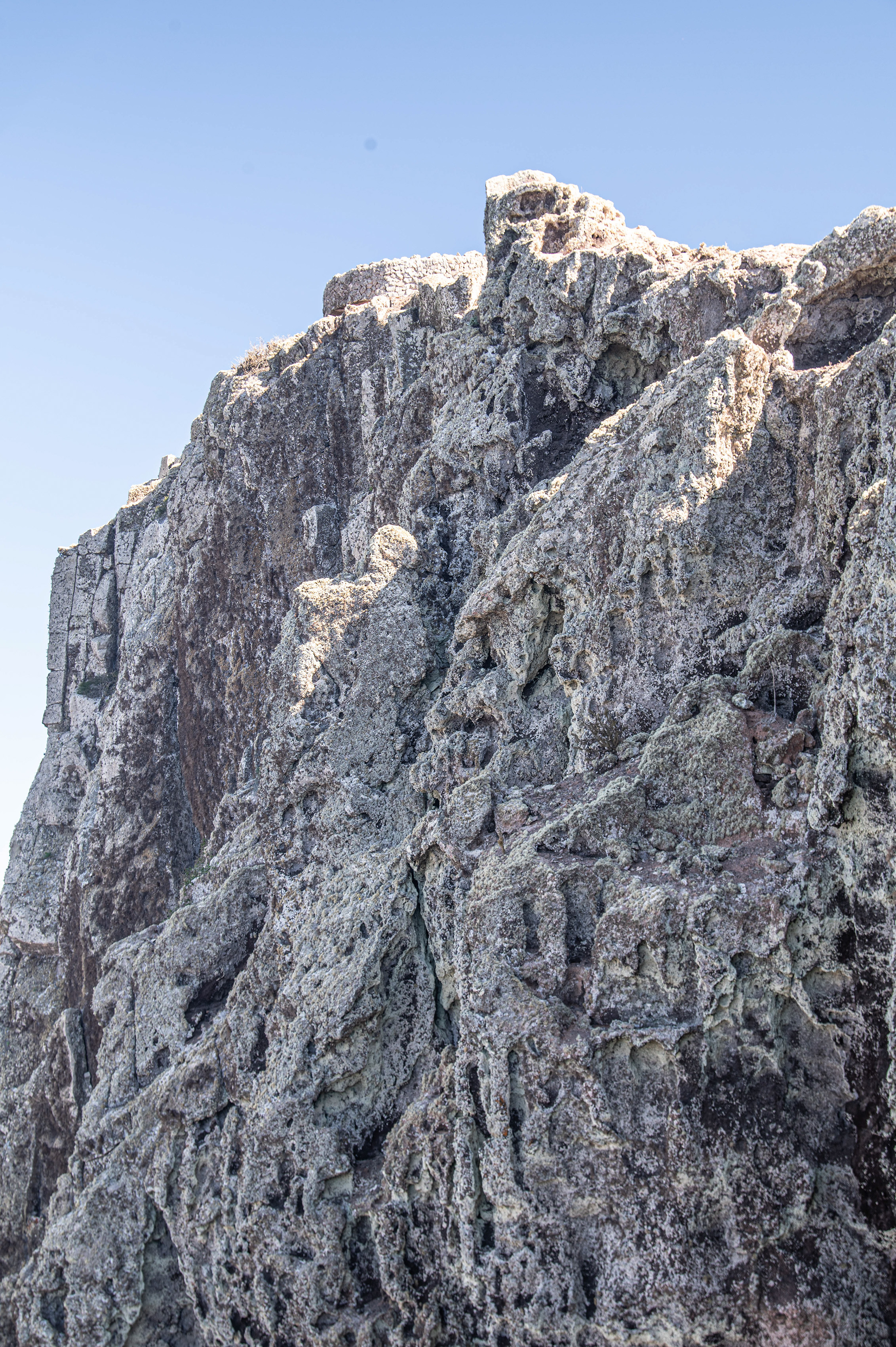a rugged, rocky cliff face against a clear sky