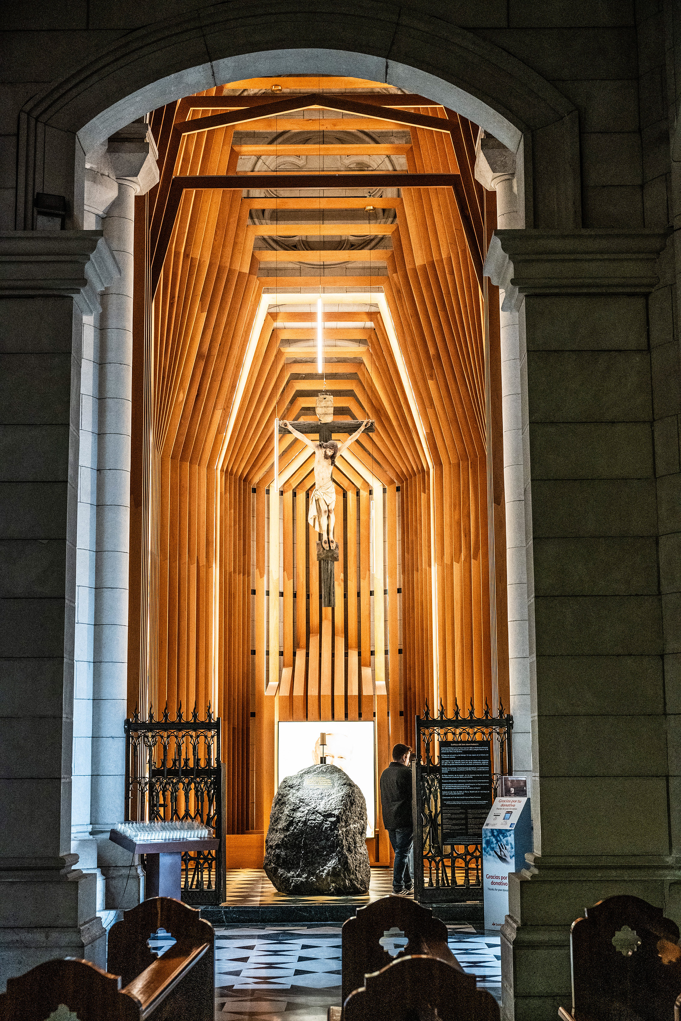 a modern, illuminated wooden structure leading to a crucifix