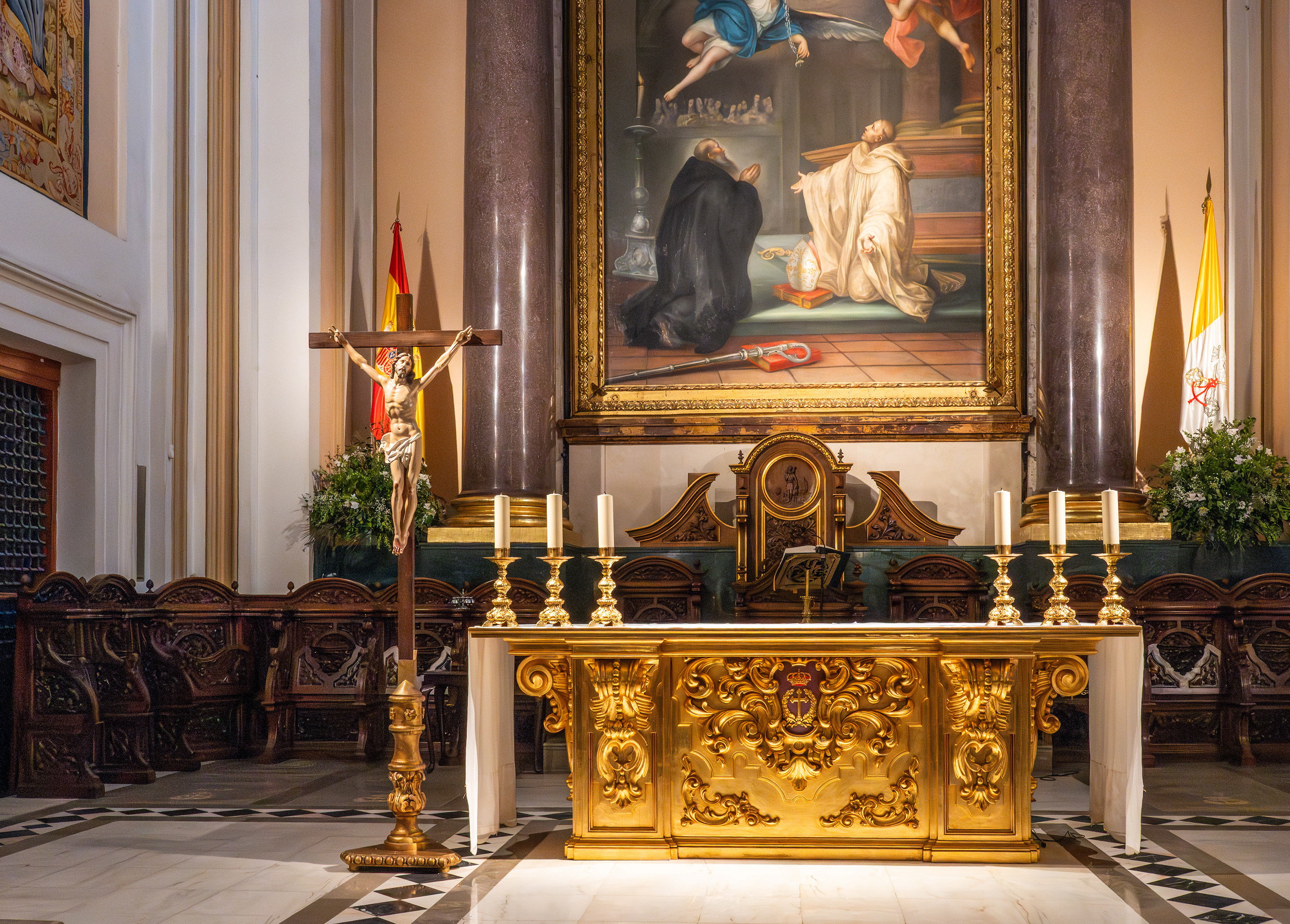 Flanking the altar are two flags with religious symbols and a crucifix with a figure of Jesus Christ