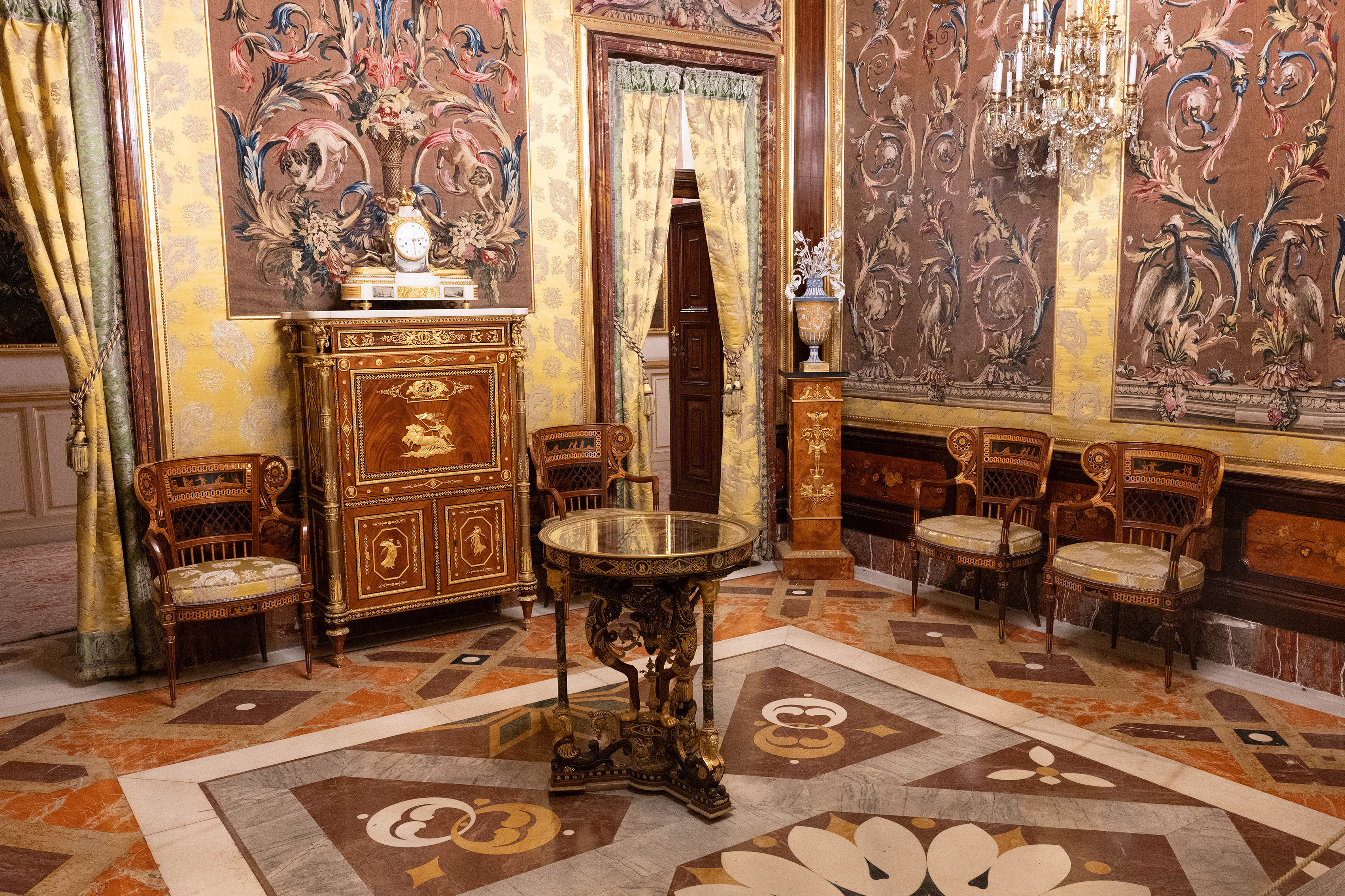 a large, intricately designed cabinet, several ornate chairs, and a small, decorative tabl