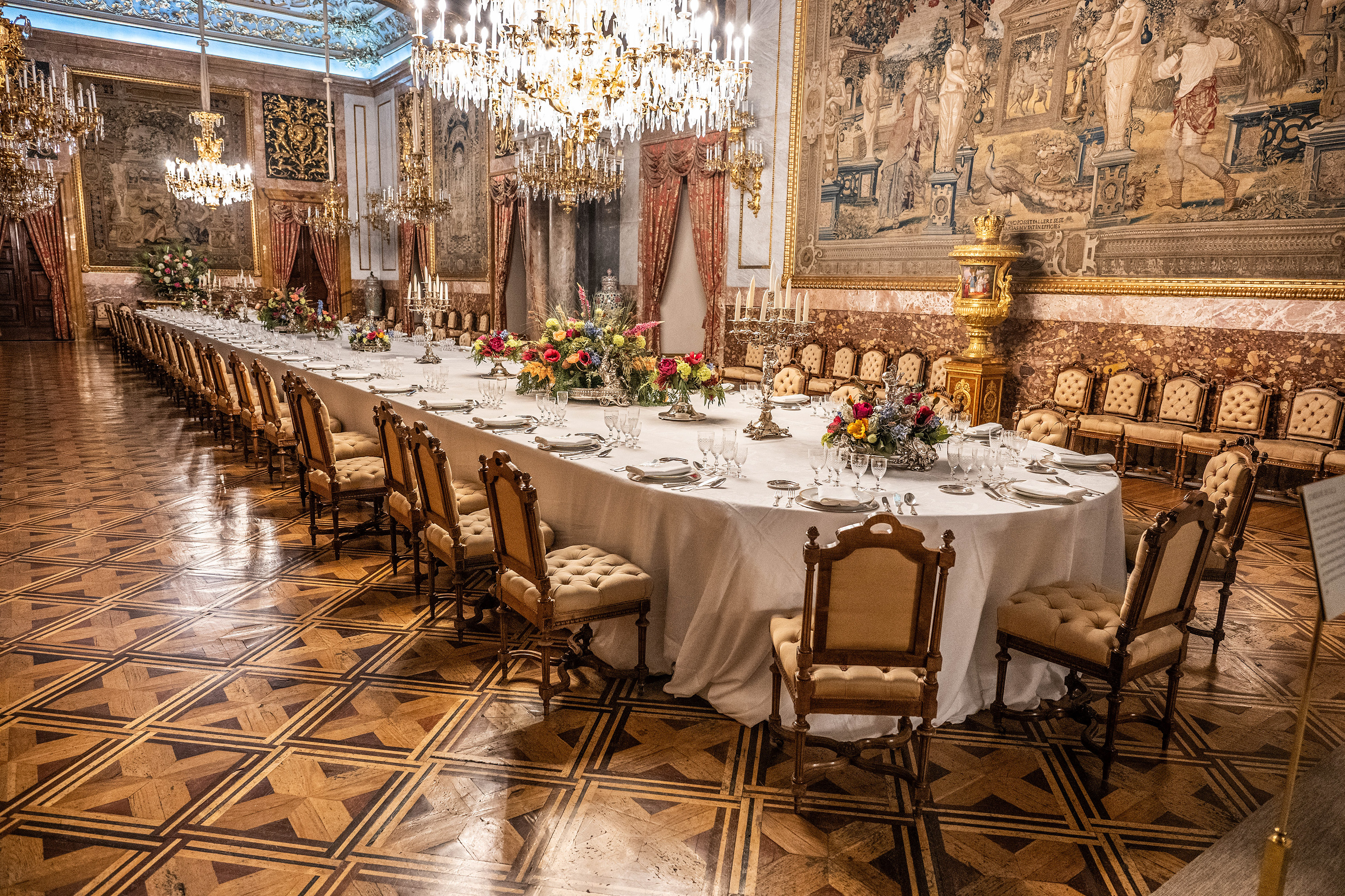an opulently decorated dining room with a long table set for a formal meal