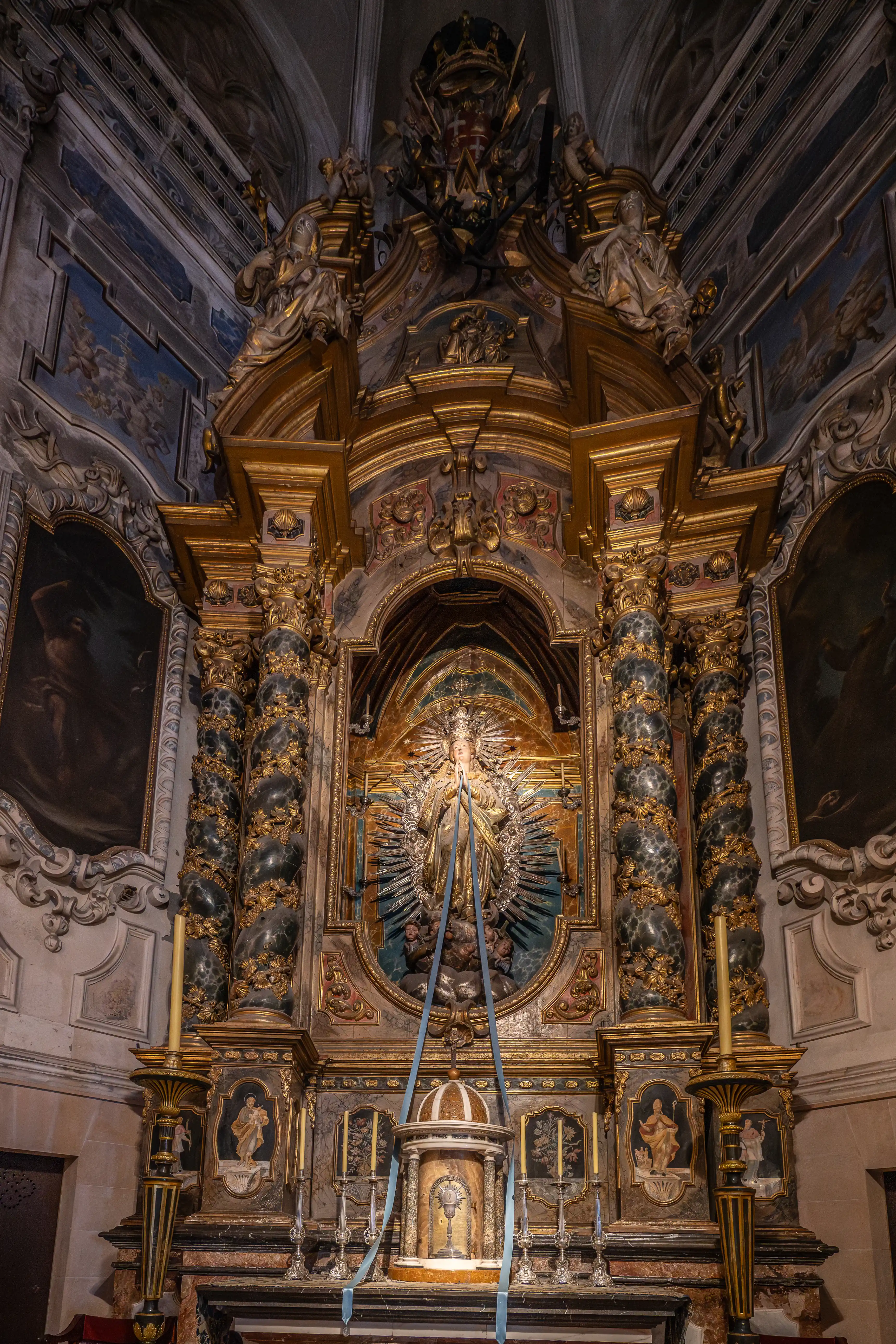 An intricately carved and gilded altar within a church, with a statue of the Virgin Mary as the central focus.