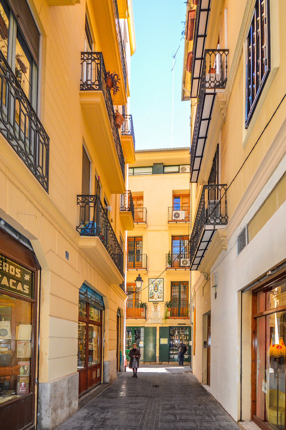 The buildings on either side are adorned with balconies featuring wrought iron railings and decorative elements