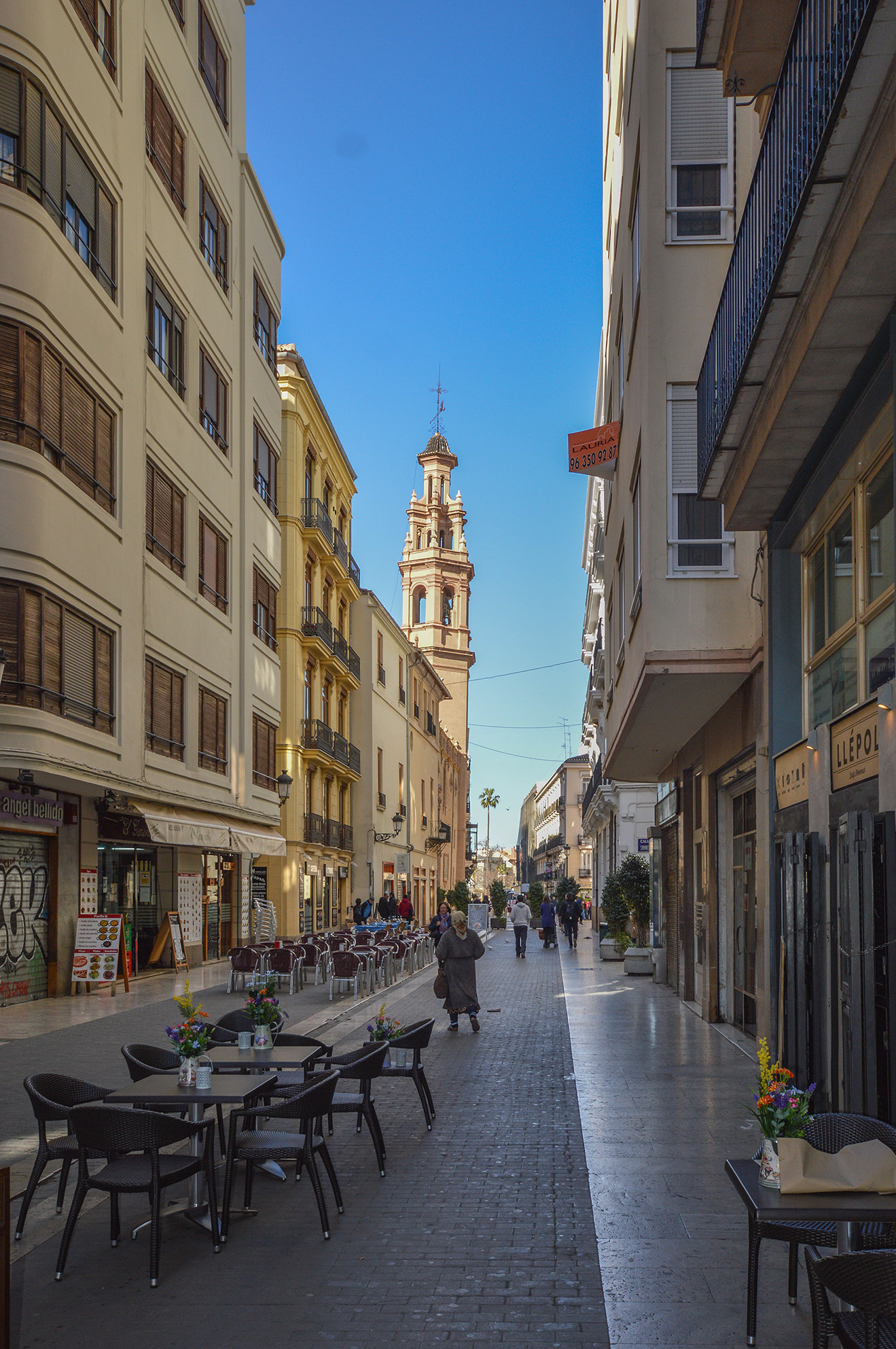 The street is paved with cobblestones and features outdoor seating for cafes and restaurants