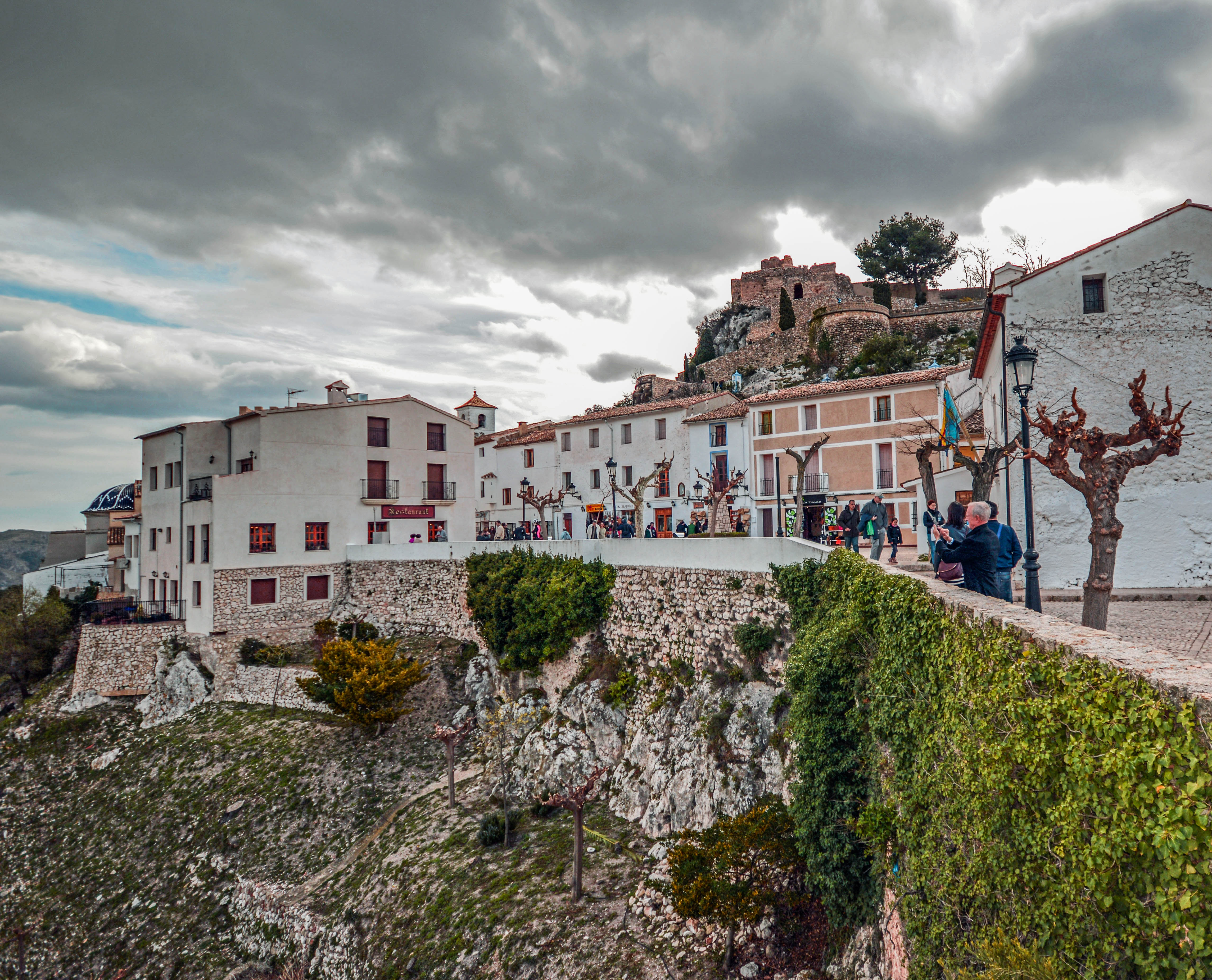 a castle on a hill, and people walking along a street