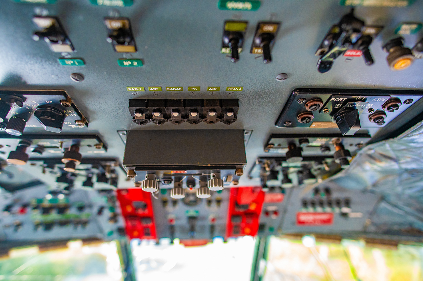 The image shows a close-up view of an aircraft's cockpit control panel, featuring various switches, buttons, and dials. The panel includes labels such as RAD.1, ADF, RADAR, PA, and RAD.2, indicating different aviation systems and controls. The switches are in different positions, suggesting they are used to operate various aircraft functions. The panel also includes circuit breakers and other components essential for the aircraft's operation. The overall layout is complex, reflecting the intricate nature of modern aviation technology.