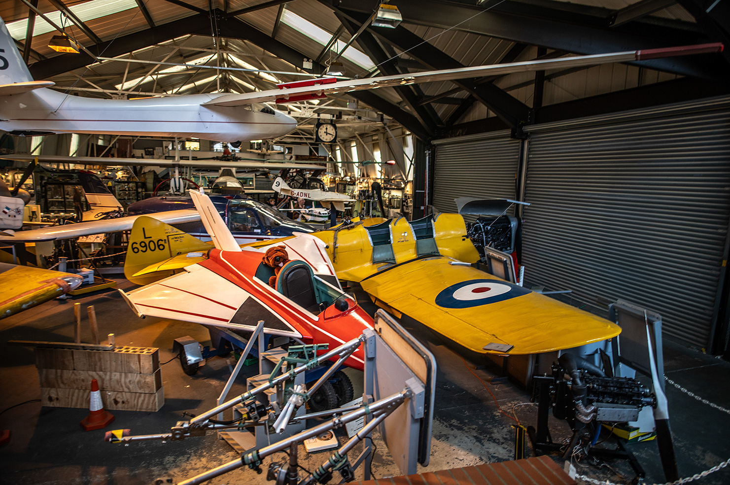 The image features the vibrant yellow cockpit and exposed engine of a vintage biplane, likely on display in a museum. Visible markings on the fuselage include 