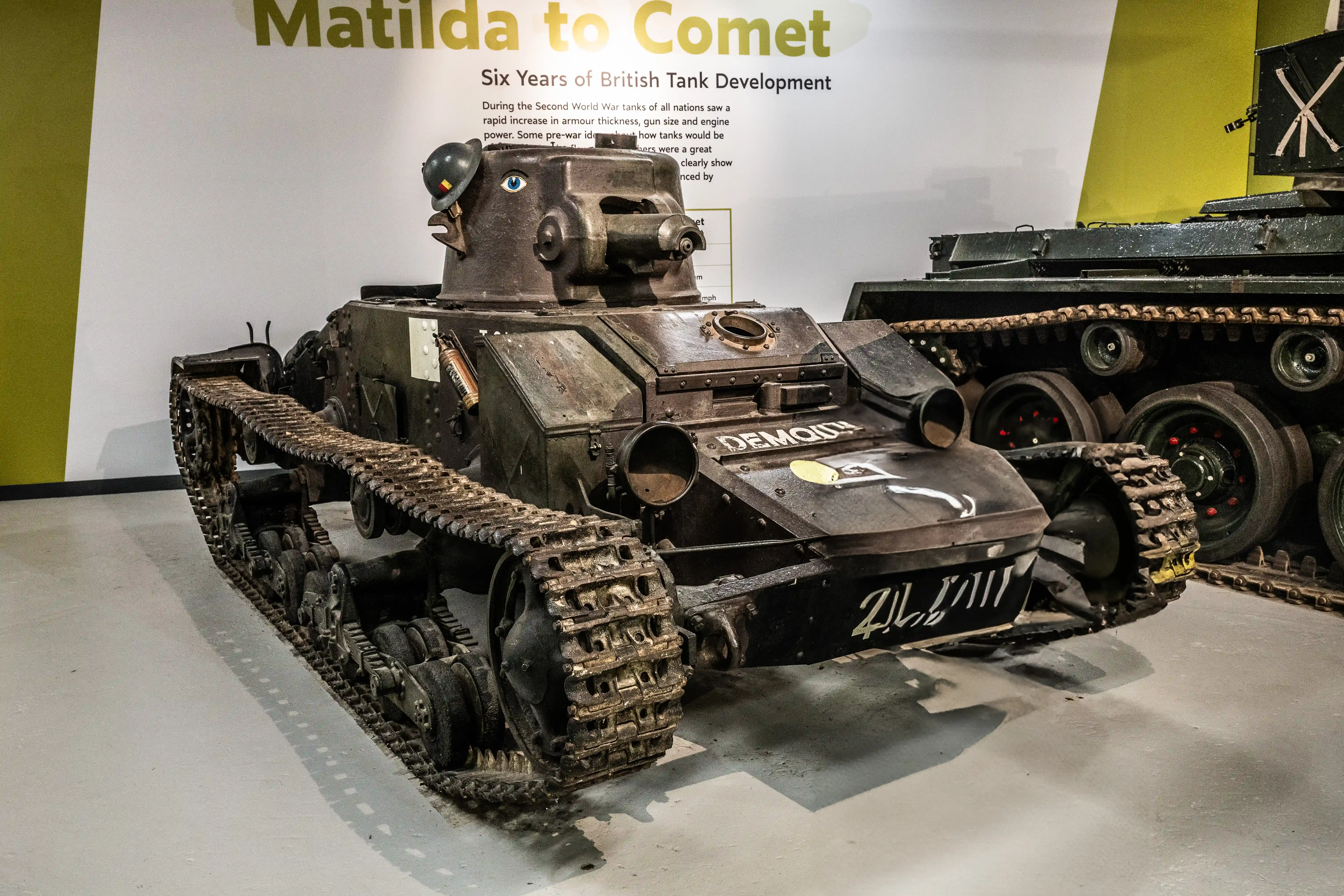 The image shows a display of British tanks, highlighting the evolution from the Matilda to the Comet, representing six years of tank development during World War II. The text mentions the rapid advancements in armor thickness, gun size, and engine power, illustrating the significant improvements in tank design and capabilities over the period.