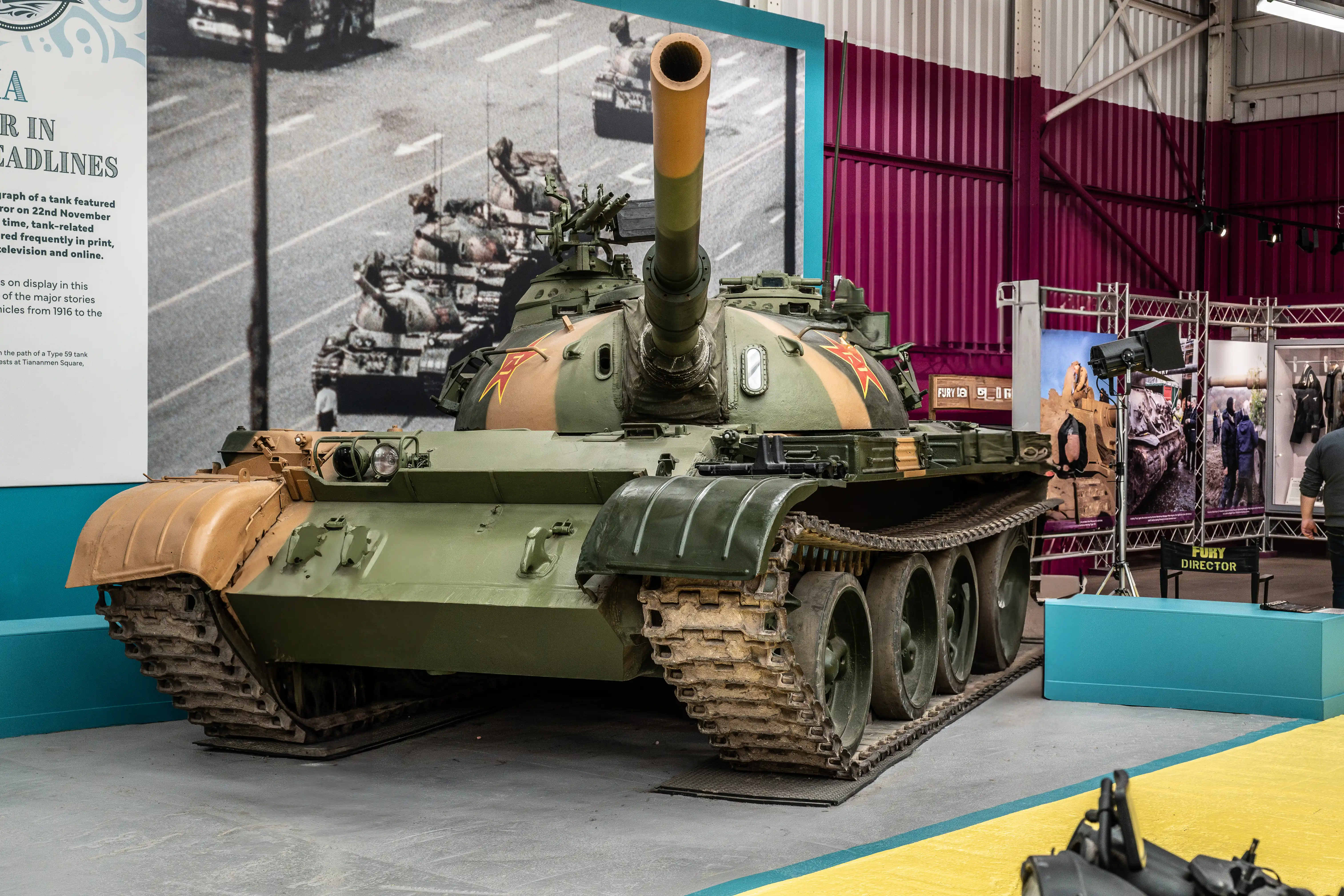 The document discusses the prominence of tanks in news headlines, noting that a photograph of a tank featured prominently in a news report on 22nd November. It highlights that tanks are frequently covered in various media formats, including print, television, and online platforms. The text also mentions a display of major tank models from 1916 to the present, including a Type 59 tank involved in the events at Tiananmen Square.