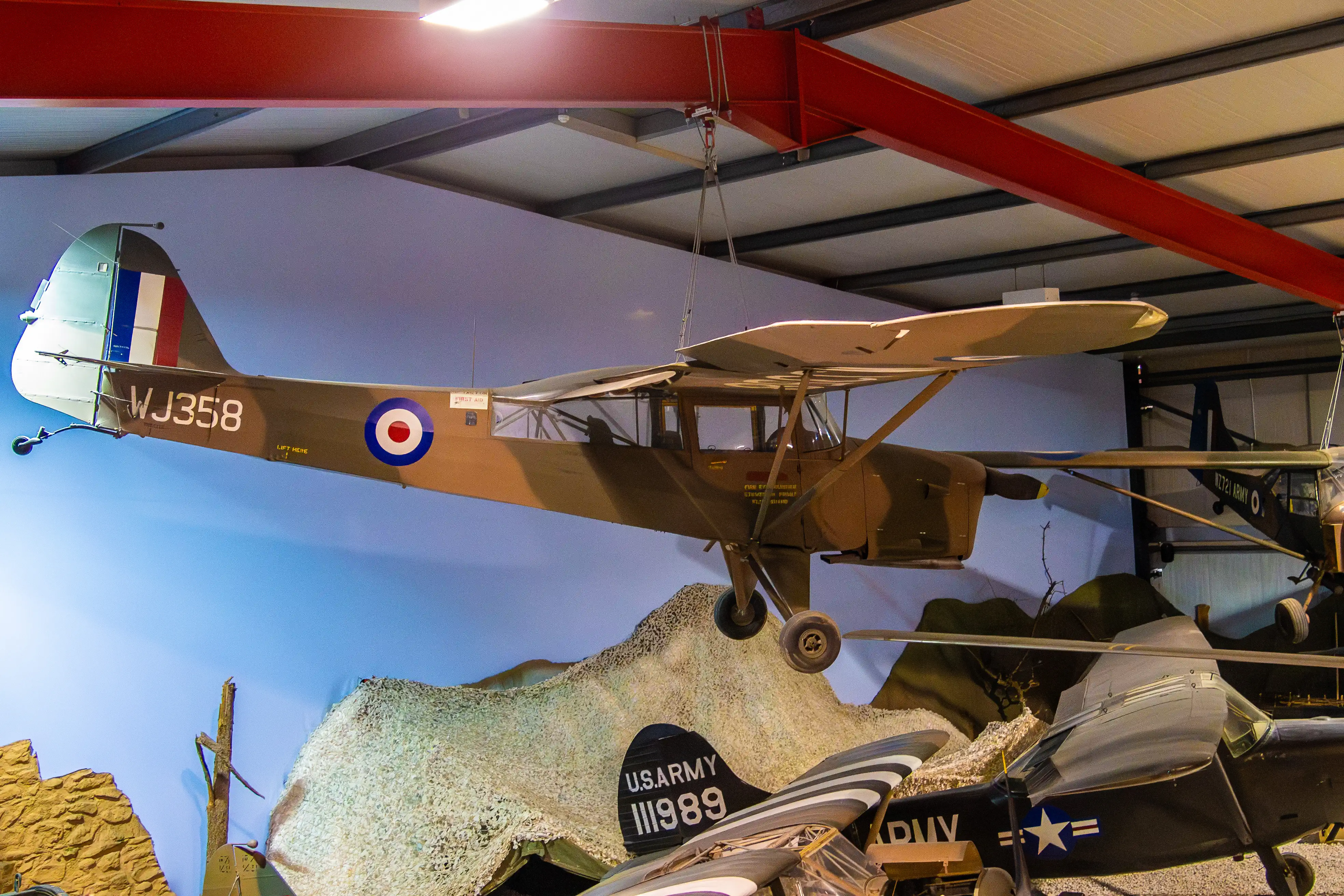 Museum display of a military Auster AOP aircraft with the circular RAF-style roundel and propeller visible. 