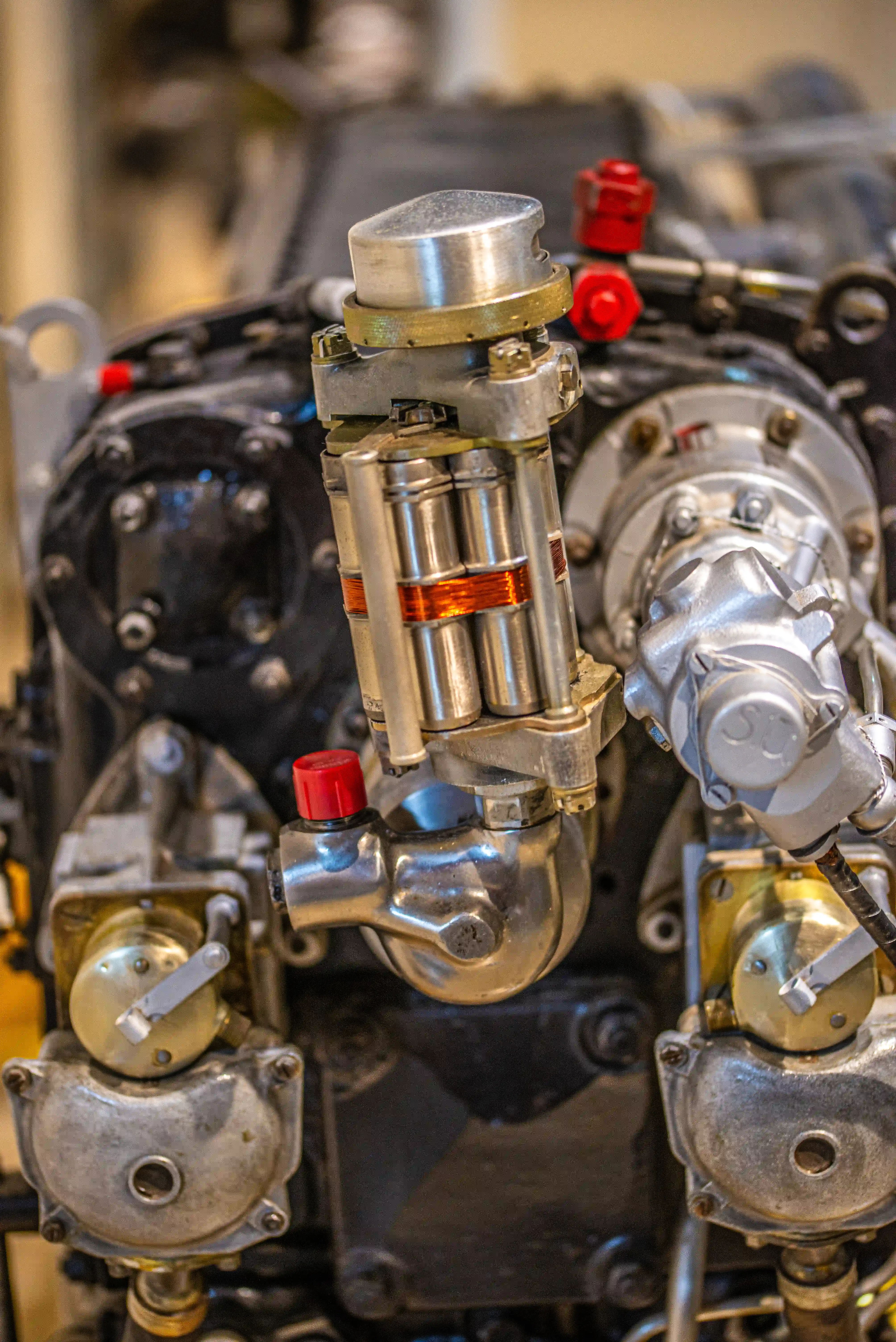 Close-up photograph of a complex mechanical assembly with metal housings, bolts, copper coils and valves.