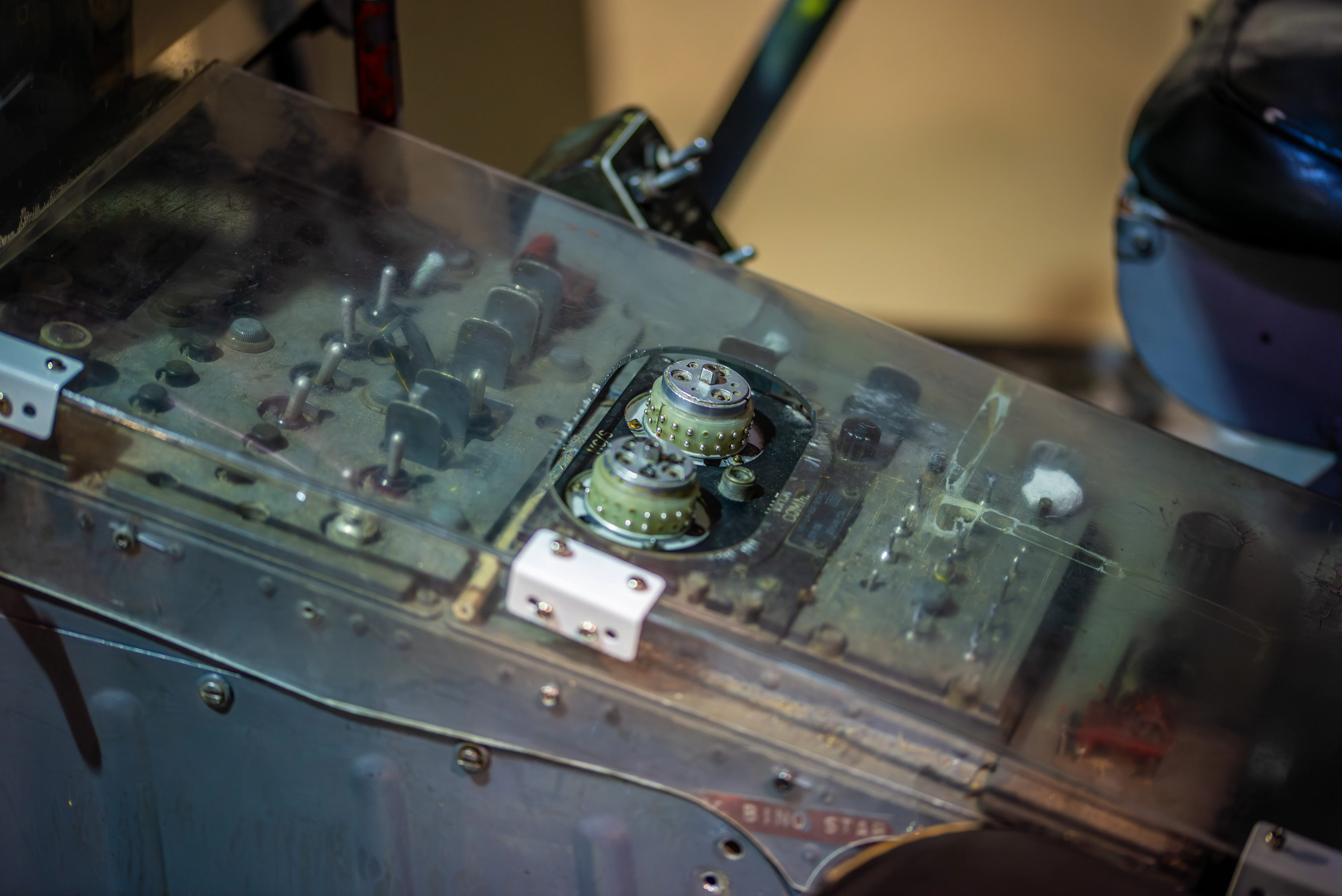 Close-up photograph of a vintage aircraft control panel with analogue switches, dials and worn metal components.