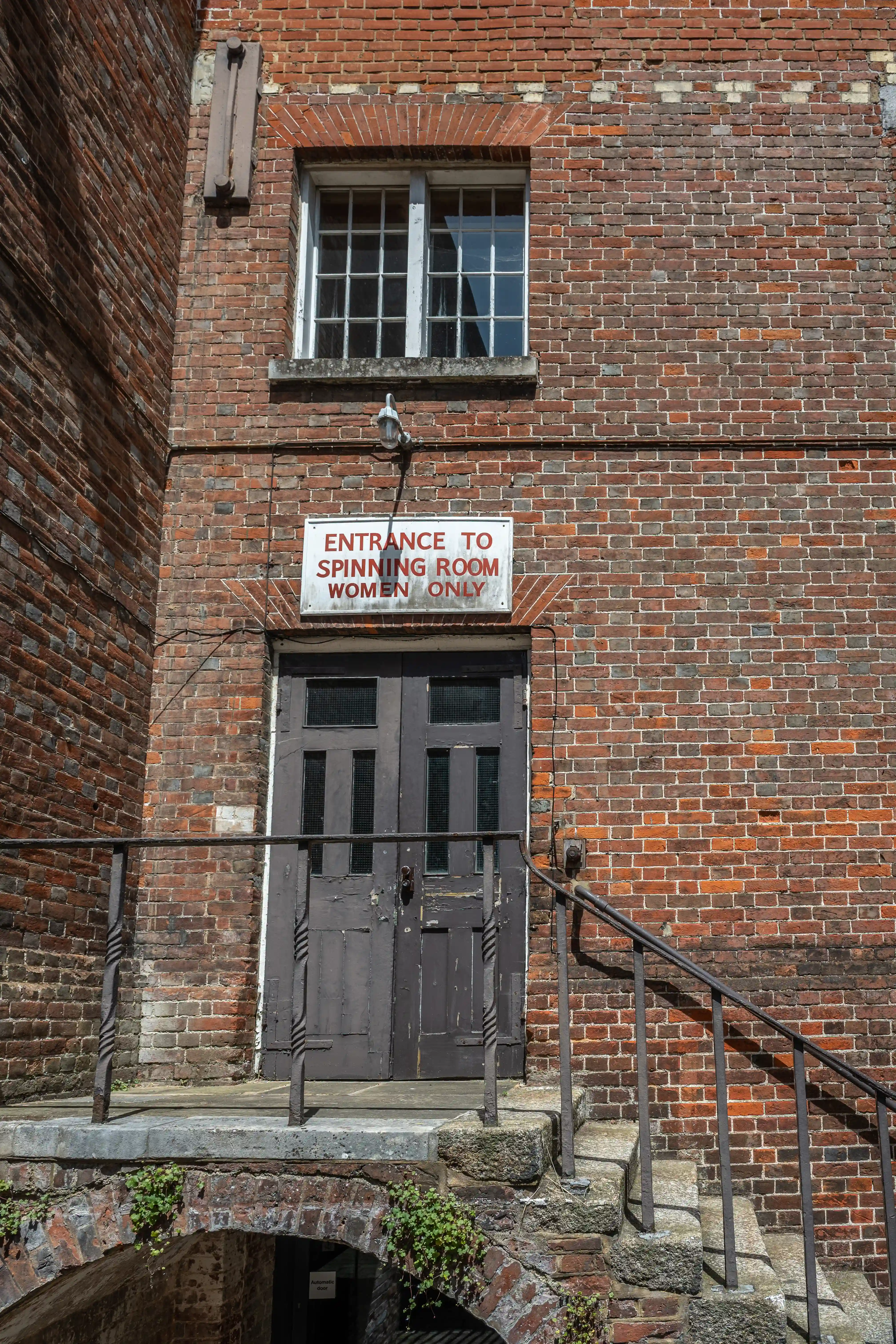 Red brick building entrance with a sign indicating 