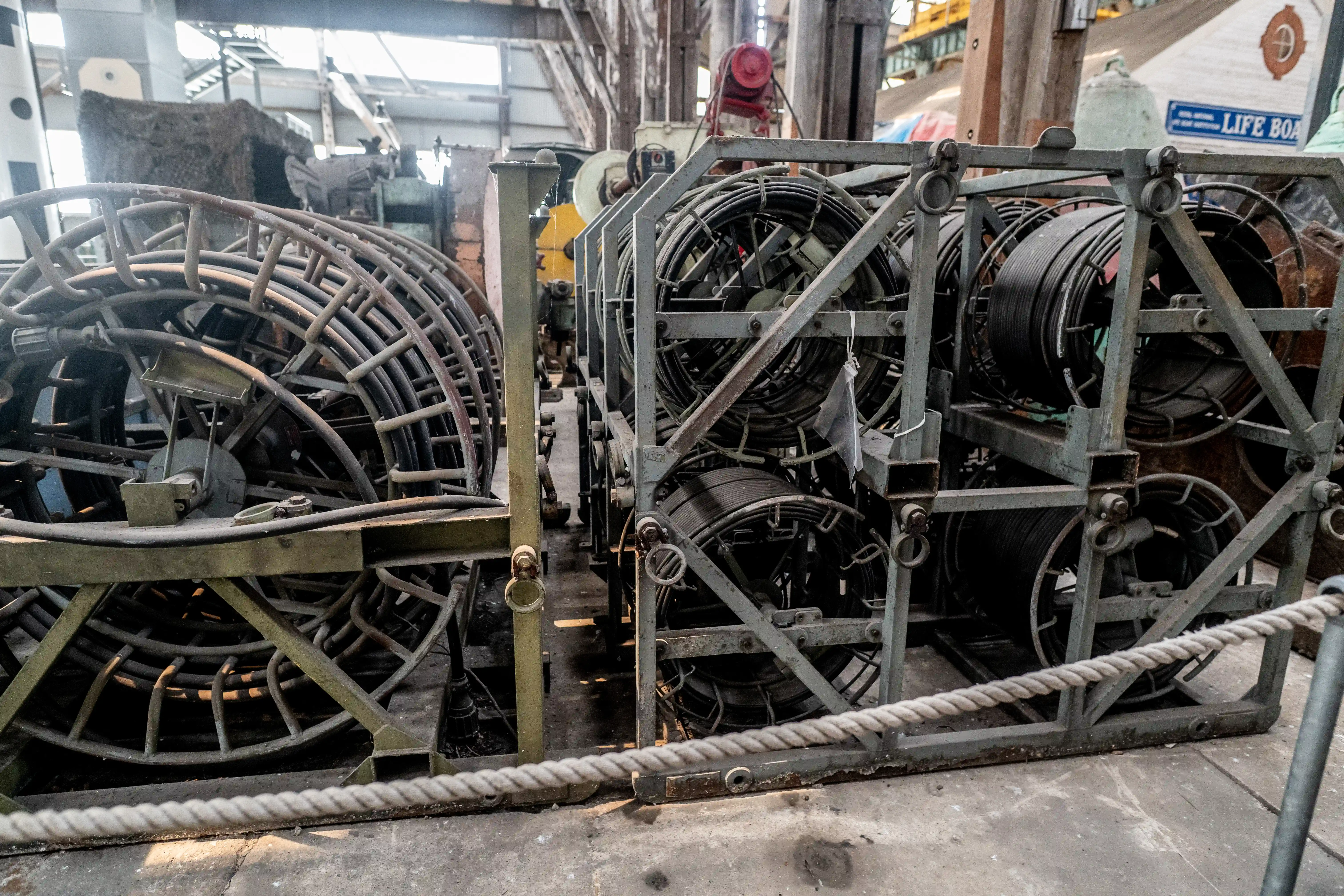 Industrial metal racks holding large spools of dark cable or rope, with a 
