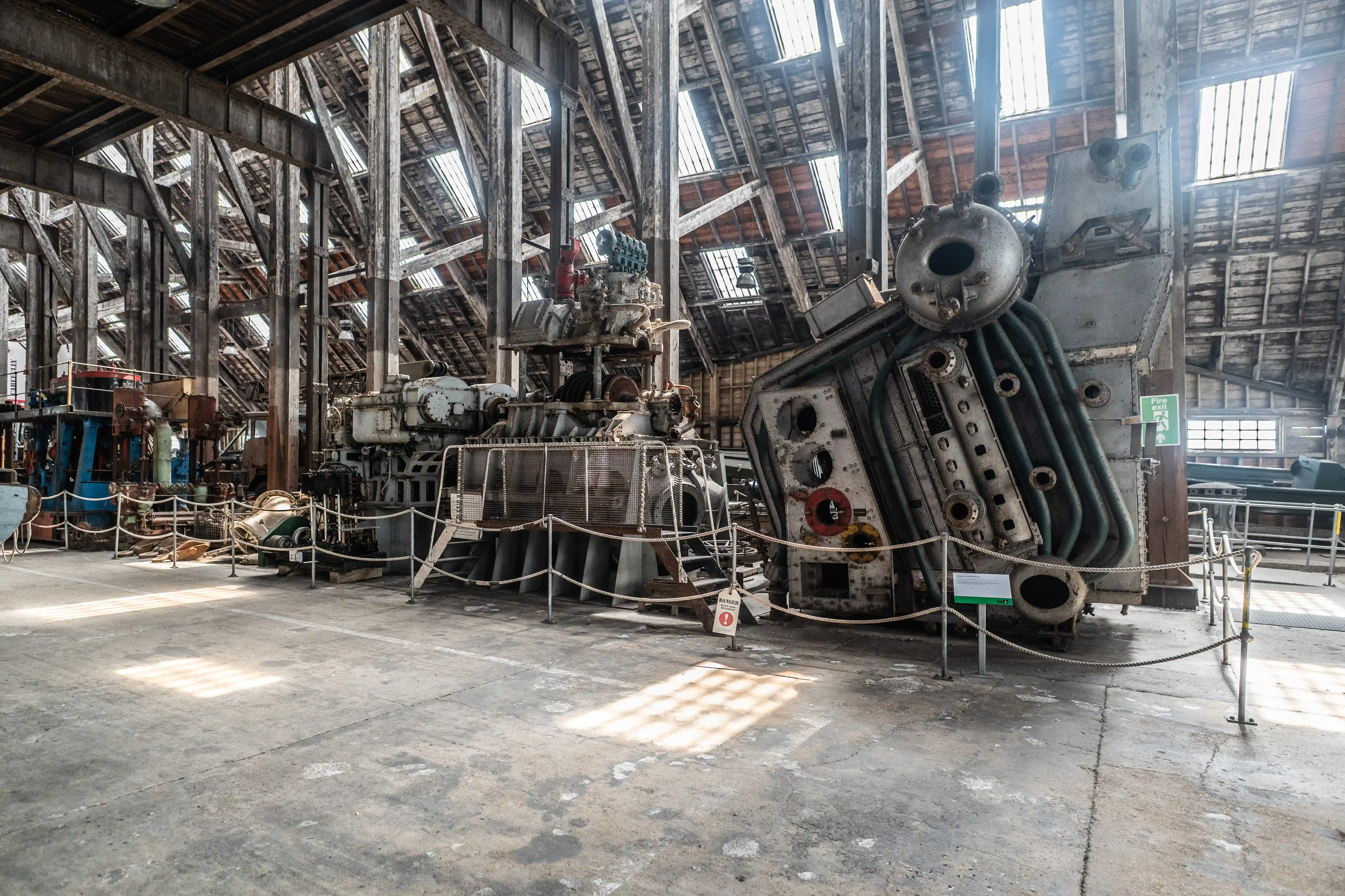  Interior view of a large industrial building with antique machinery and skylights.