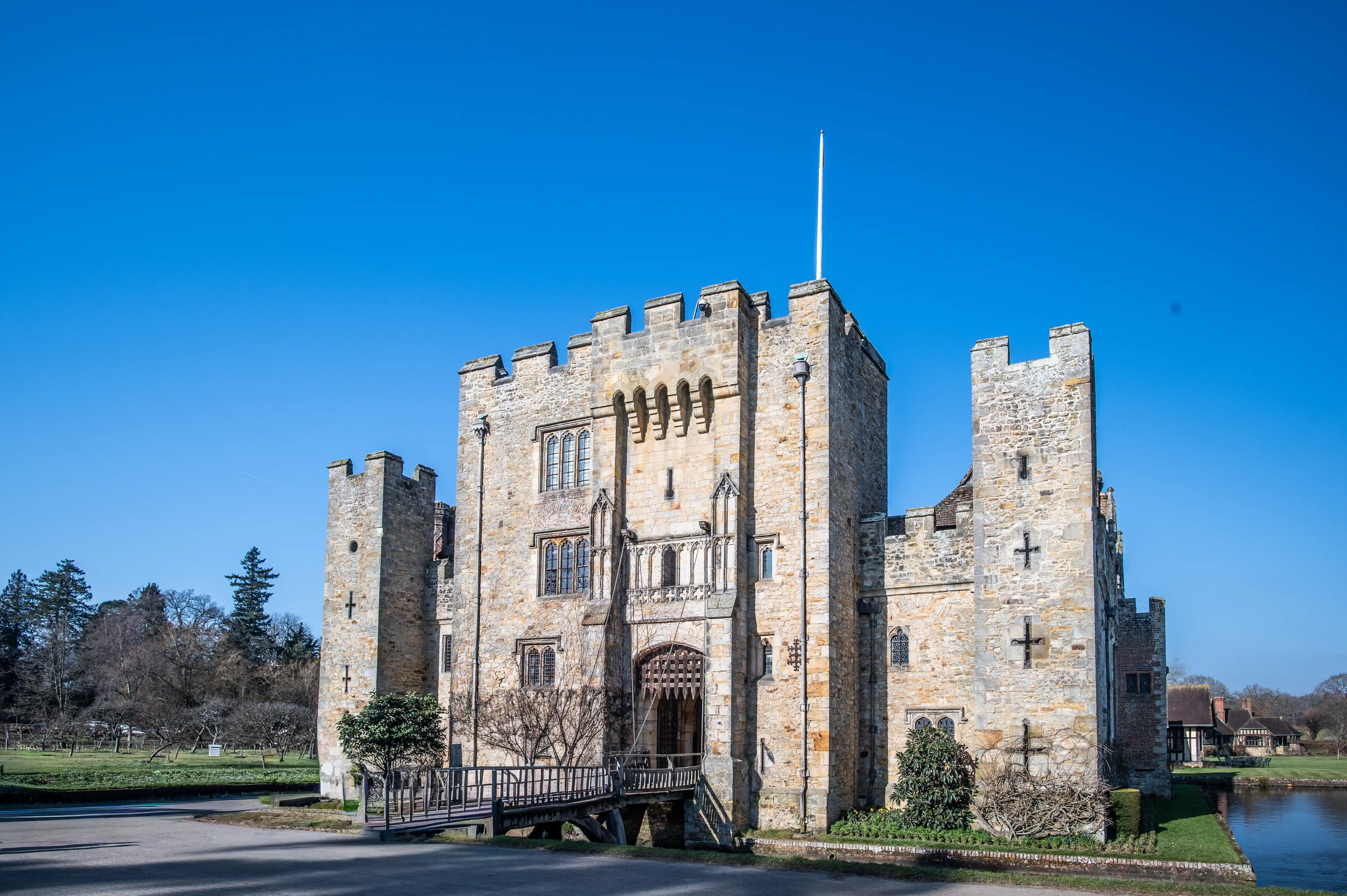 A medieval stone castle with a drawbridge and flagpole, under a clear blue sky.