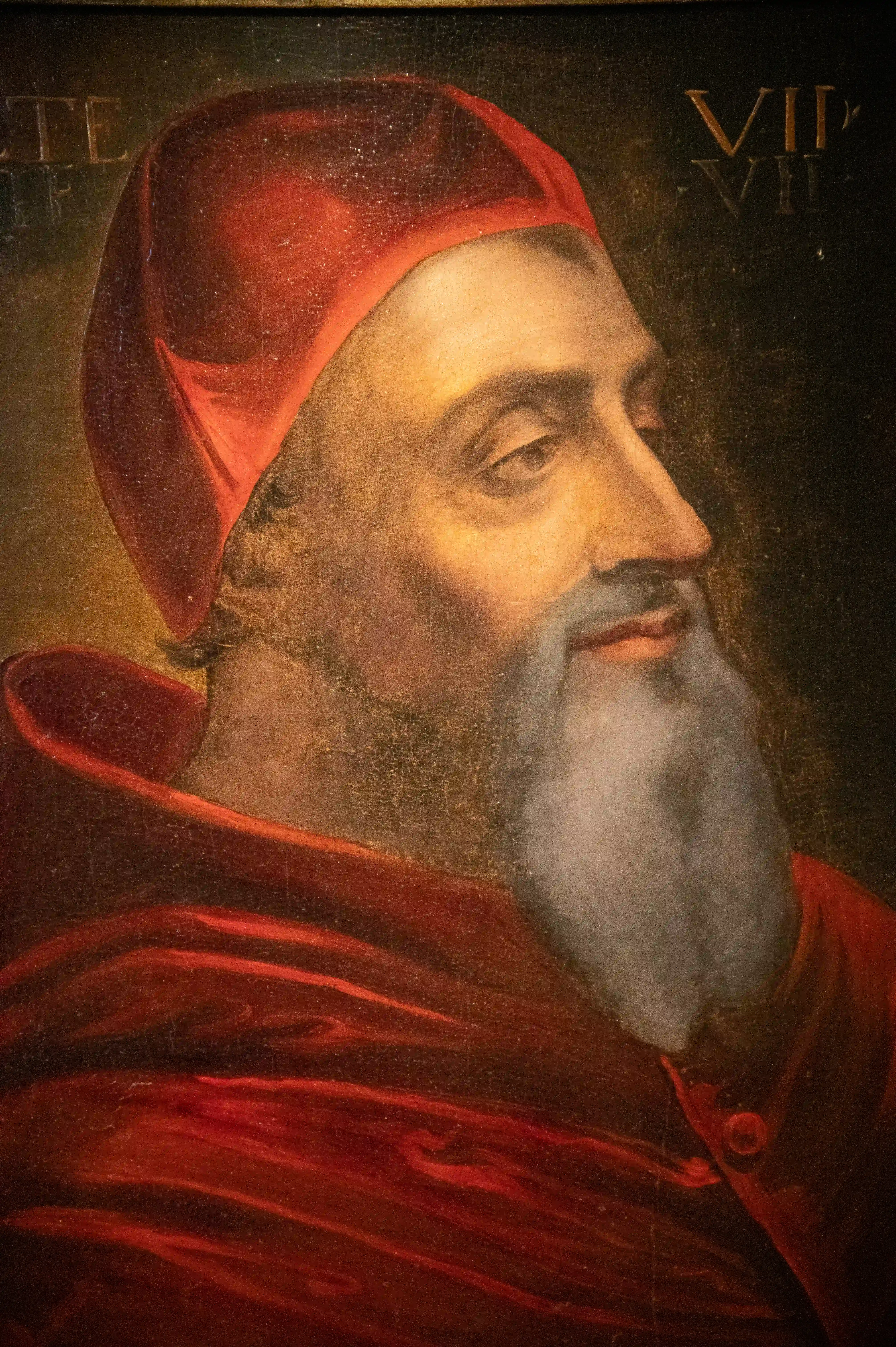 A painted portrait of a bearded man wearing a red clerical cap and robes, looking to the right.