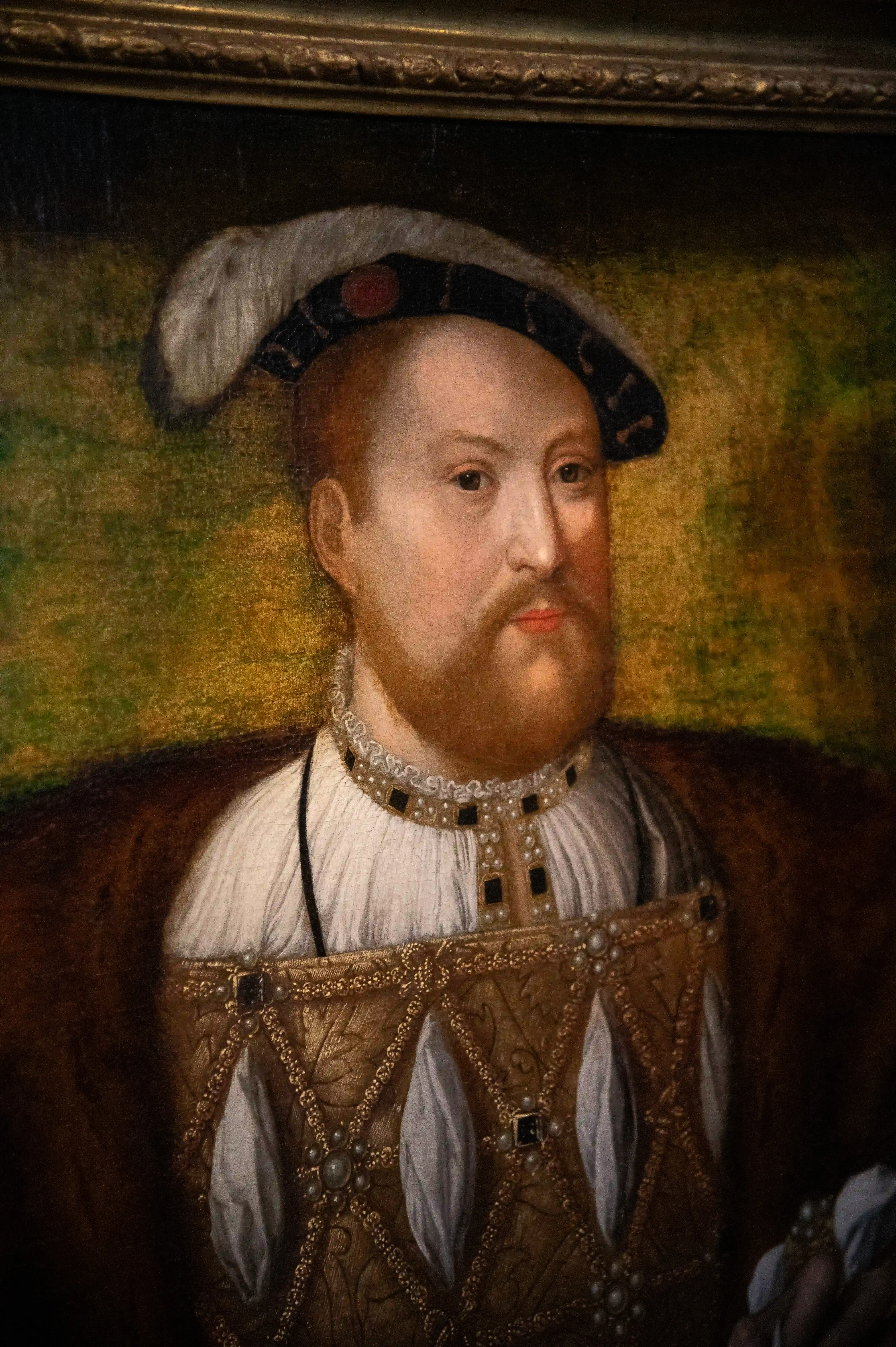 A painted portrait of a man in Tudor-era clothing, featuring a feathered cap, ruffled collar, and a jeweled doublet.