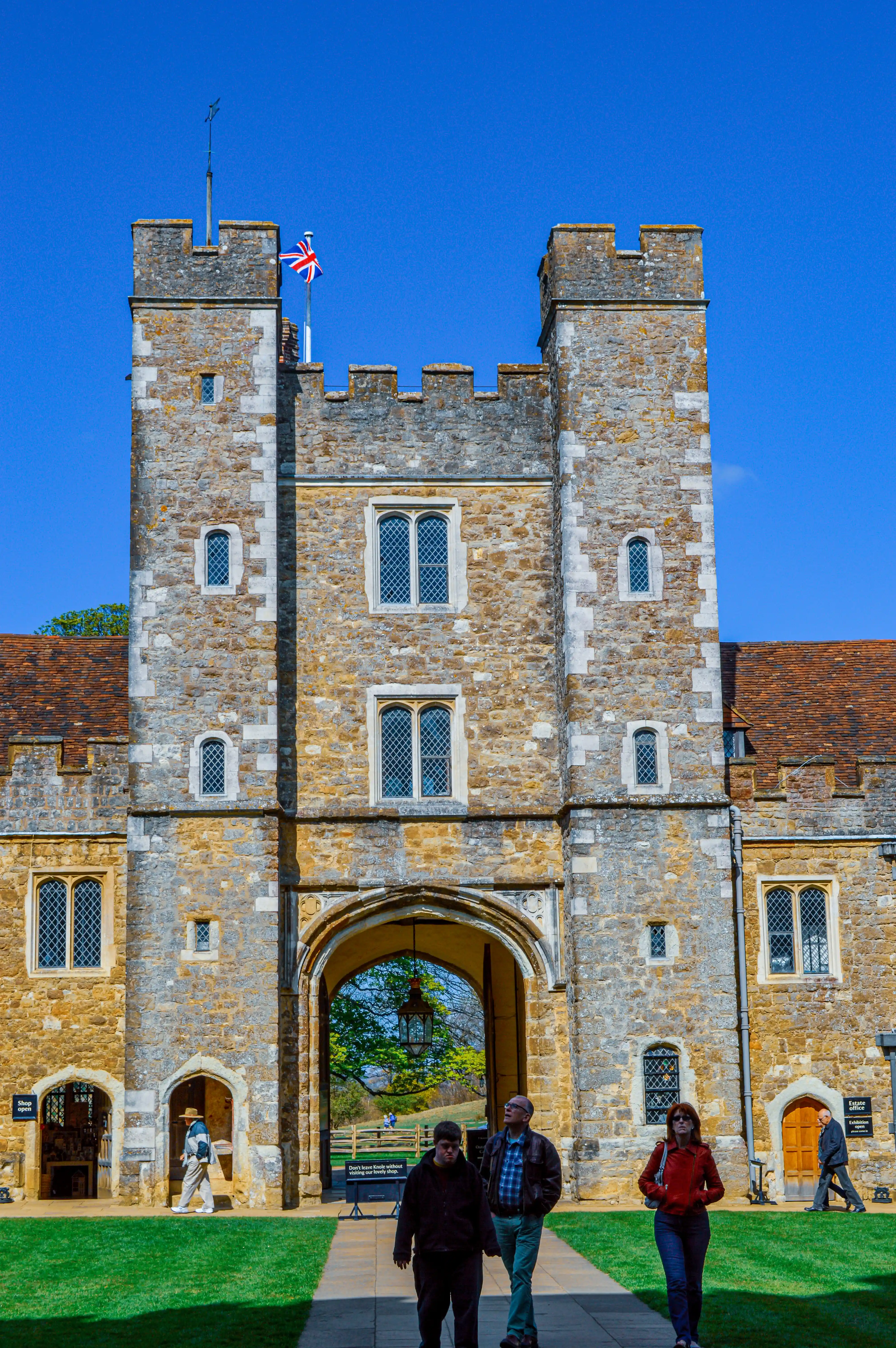A stone archway frames a partially open, dark wooden door. The stonework is rough-hewn and ancient. Beyond the door, a brightly lit interior with another smaller, arched doorway is visible.v