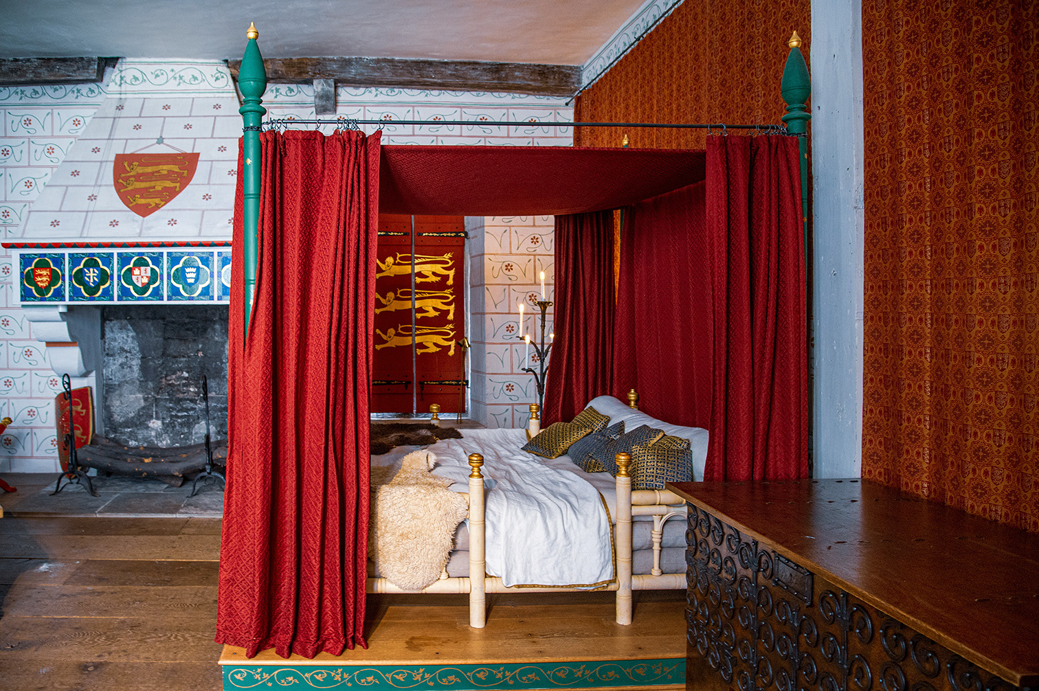 a richly decorated bedroom with a large, canopied bed draped in red curtains