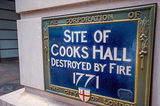 The image shows a plaque indicating the site of Cooks Hall, which was destroyed by fire in 1771. The plaque is affixed by the Corporation of the City of London.