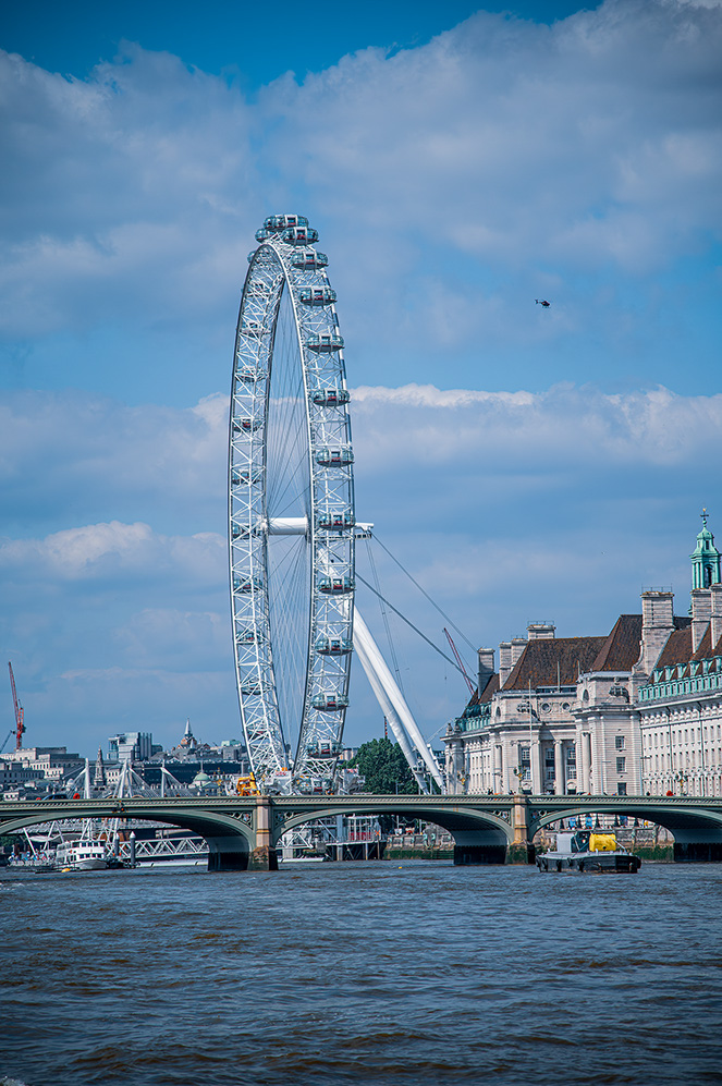 The document describes a prominent landmark, the London Eye, a giant Ferris wheel situated on the South Bank of the River Thames in London. It highlights the structure's height, its glass capsules for visitor seating, and its status as a significant tourist attraction. The text also mentions nearby landmarks such as the County Hall and the River Thames, and notes the presence of a helicopter in the sky.