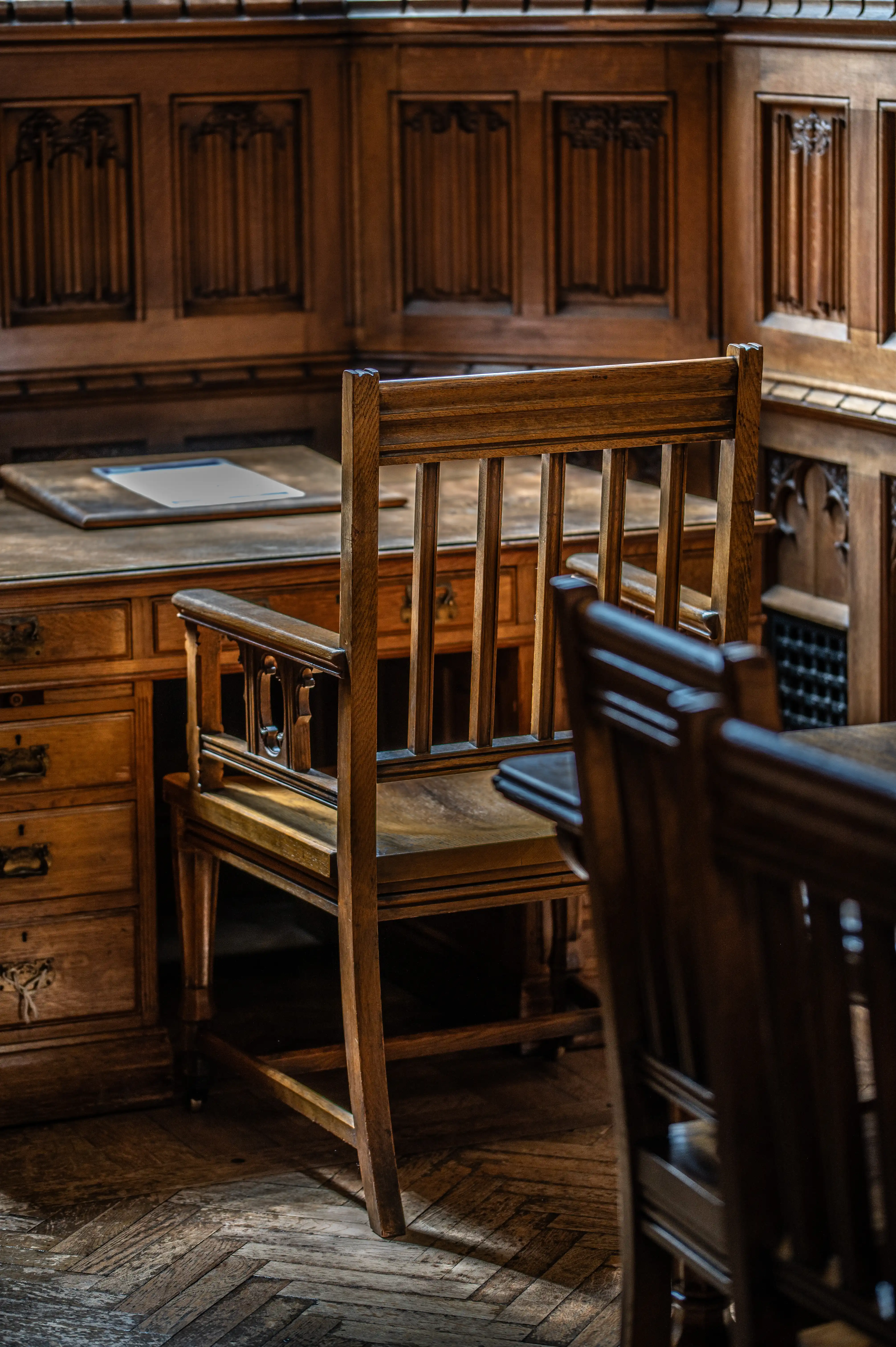 Wooden chair with slatted back in a historic library reading room, with desks and panelled walls in the background