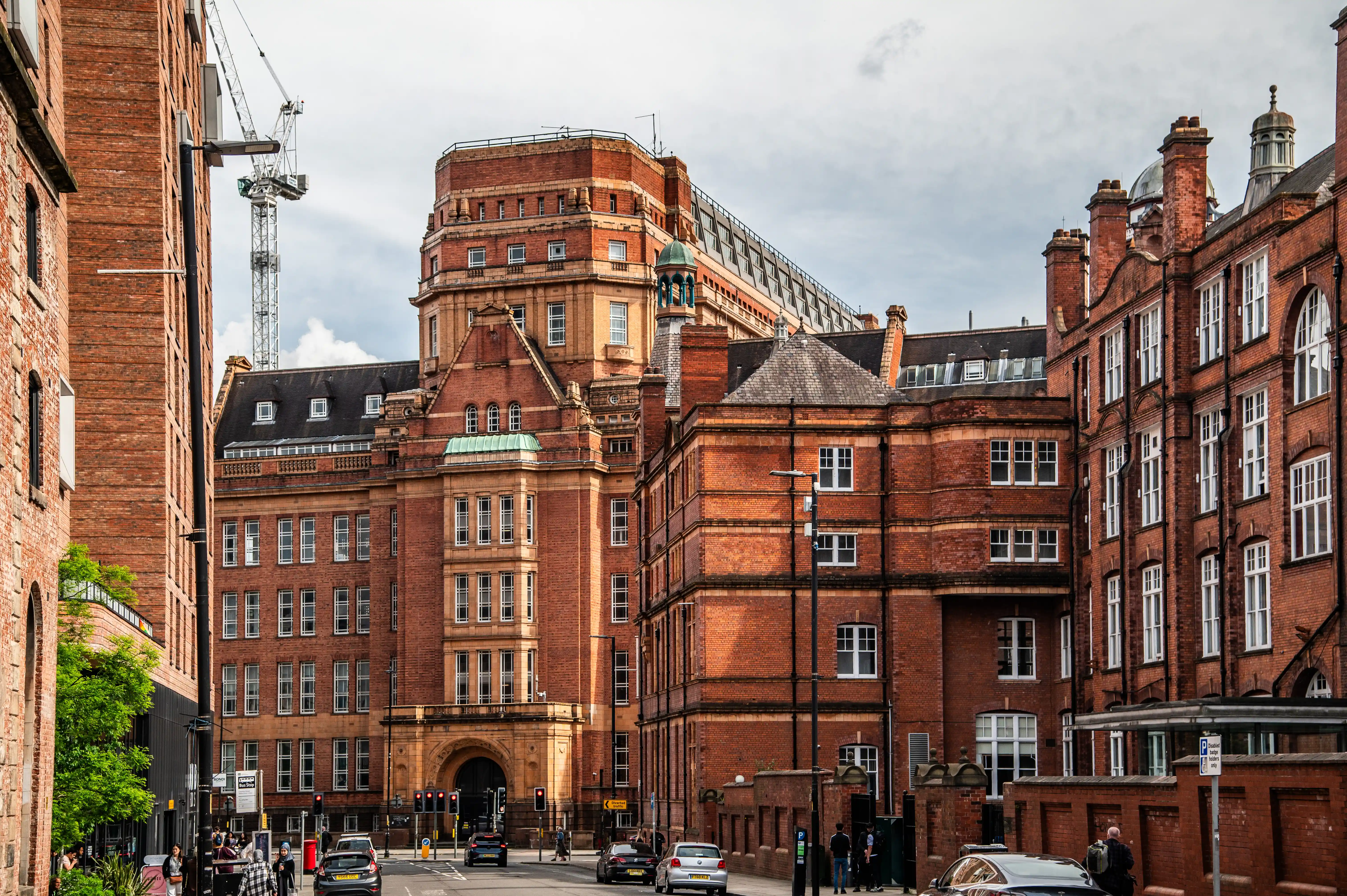 Red brick buildings with white windows and a tower crane in the background on a city street.