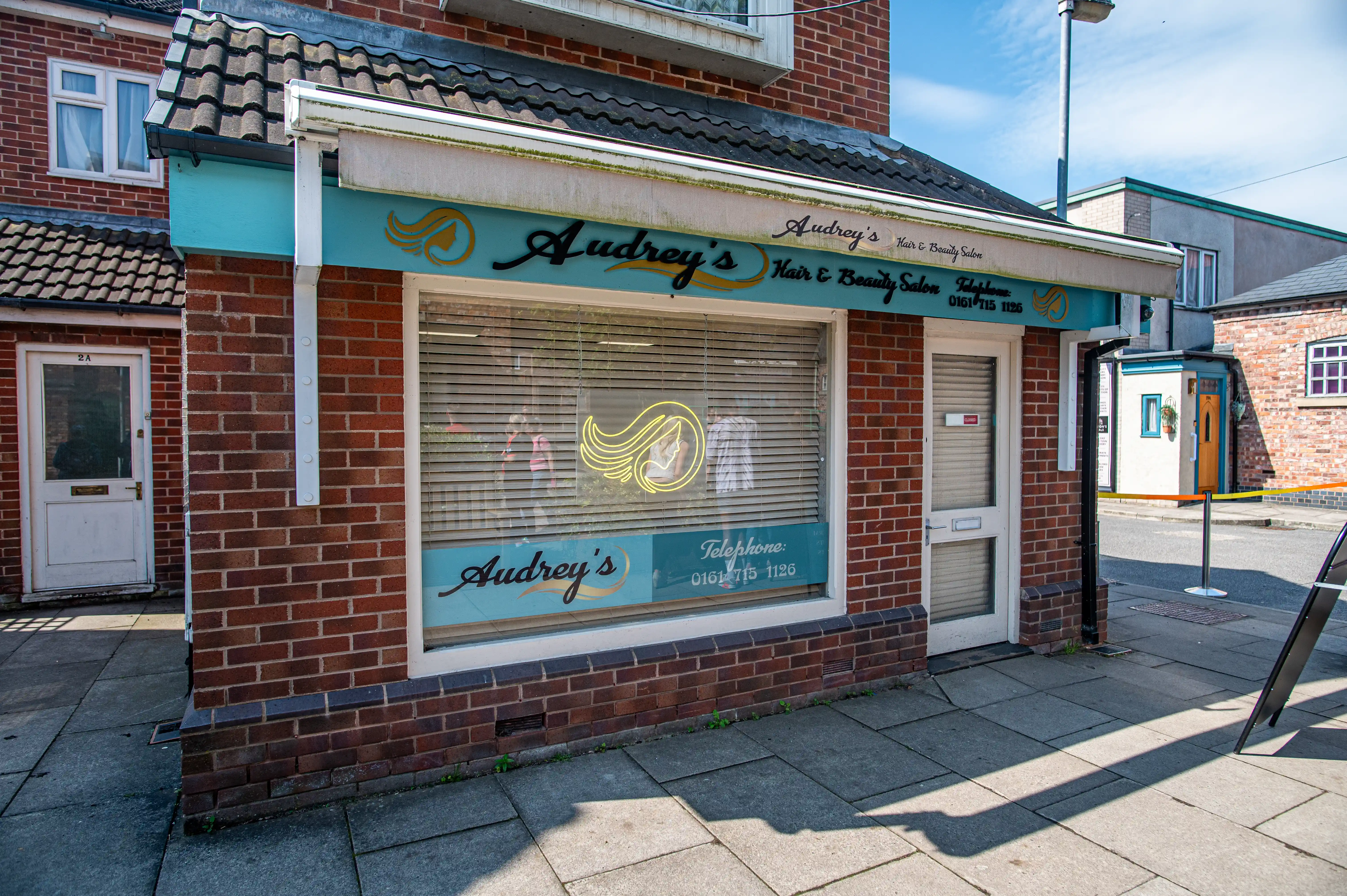 Exterior view of Audrey's Hair & Beauty Salon, a brick building with a teal awning and signage.
