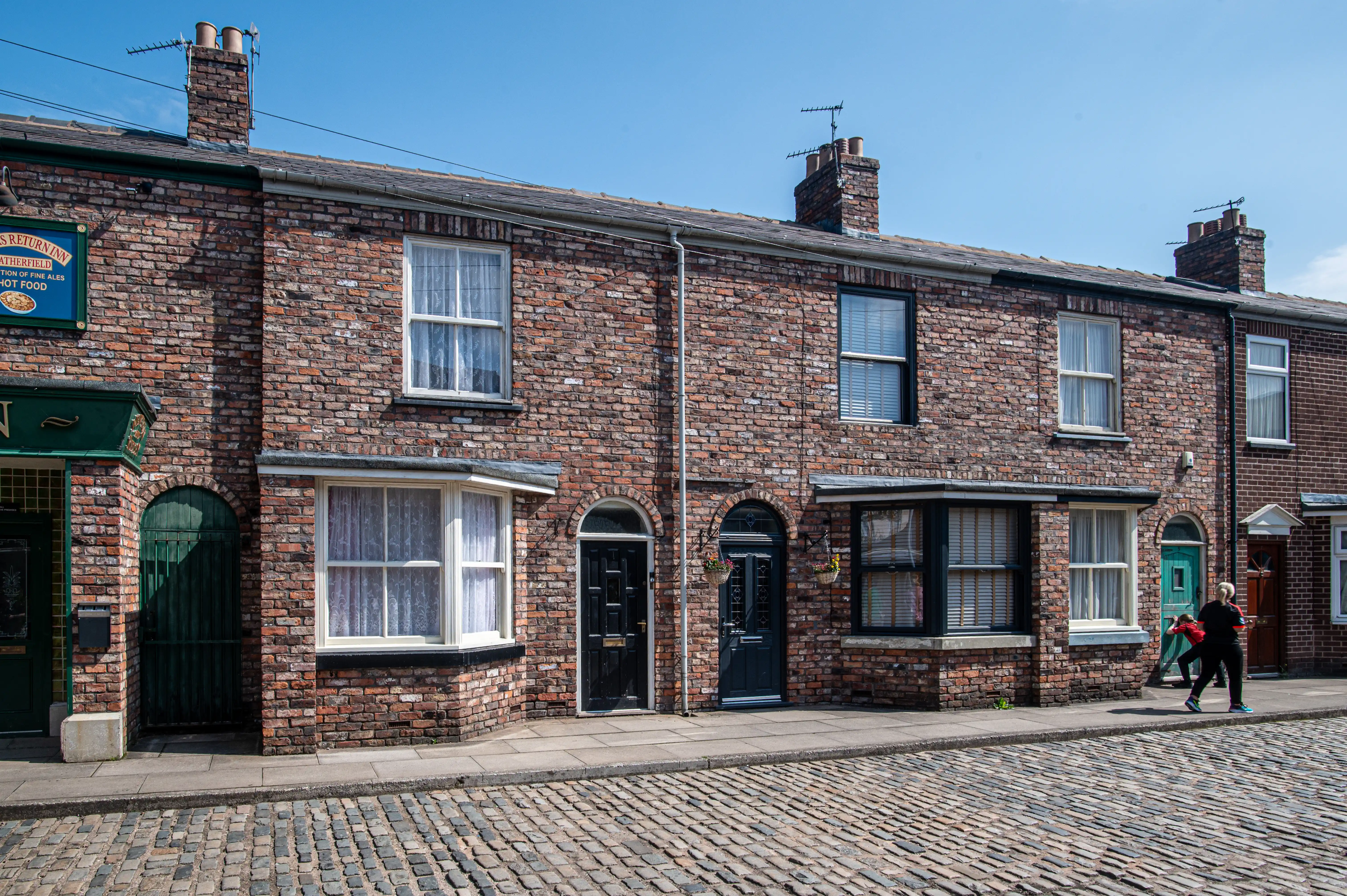 Terraced brick houses with bay windows and cobblestone street, typical of the Coronation Street set.