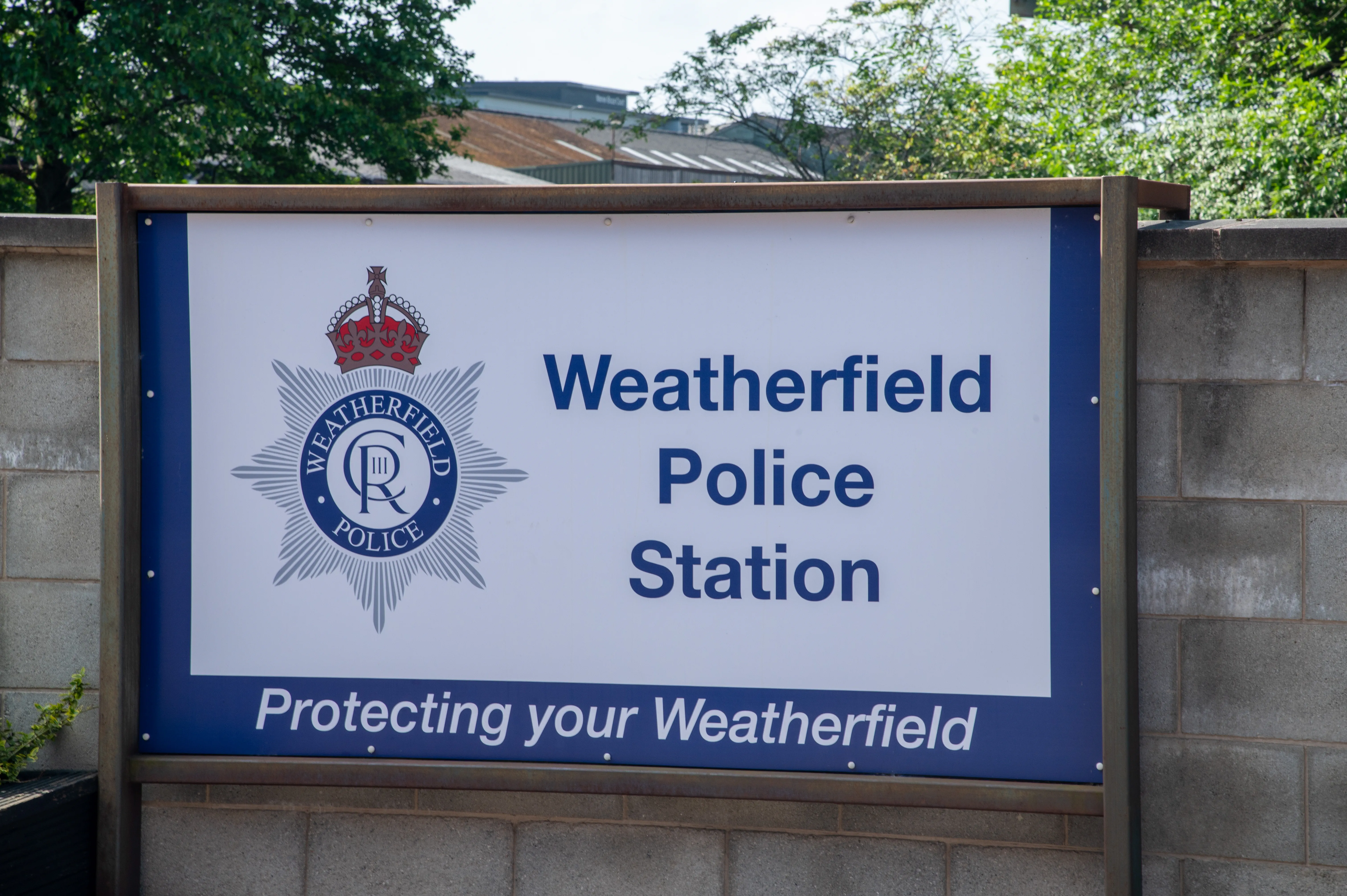 A sign for Weatherfield Police Station, featuring the police emblem and the text &laquo;Weatherfield Police Station&raquo; and &laquo;Protecting your Weatherfield&raquo;.
