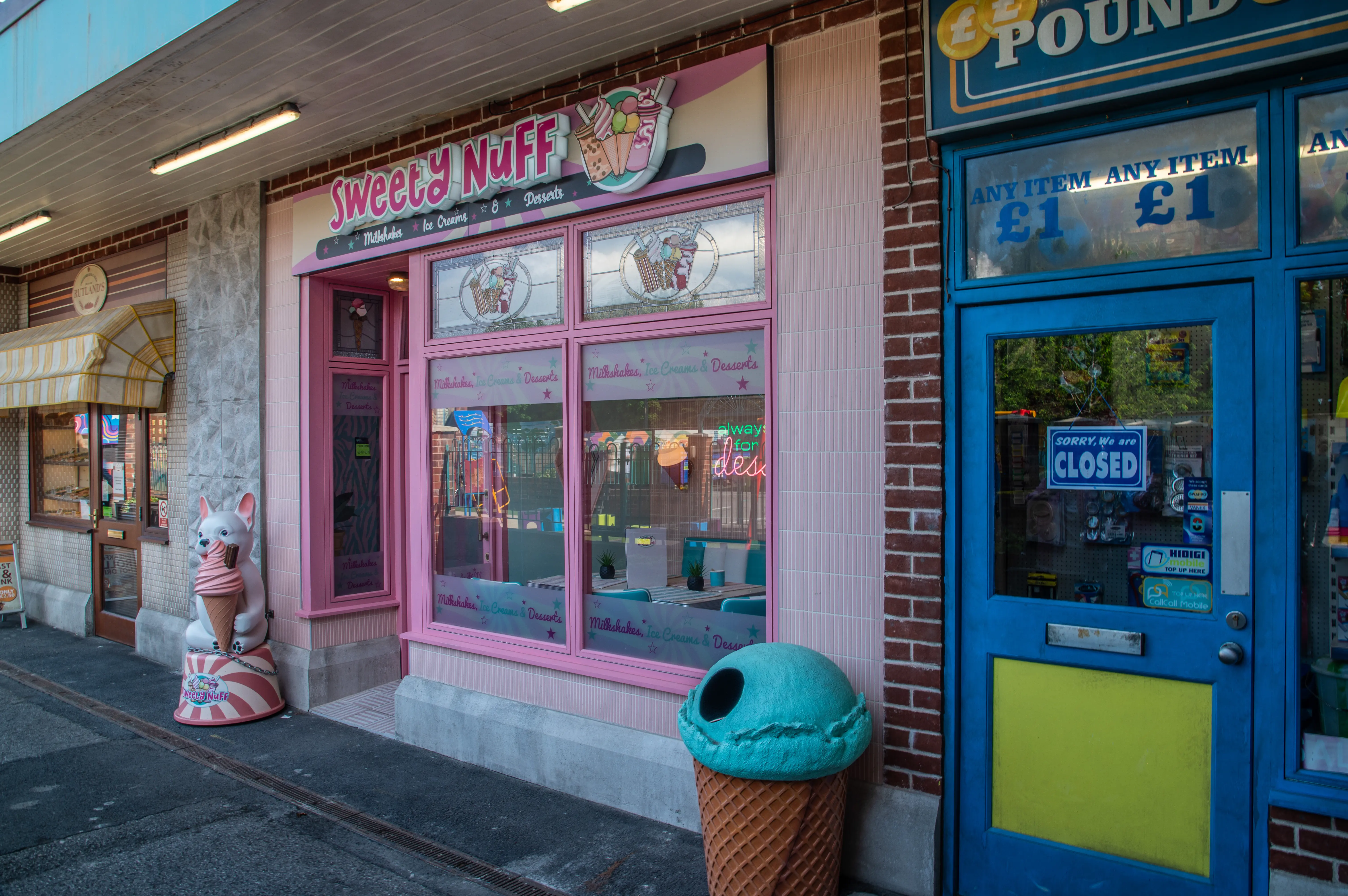 A pink ice cream shop called Sweety Nuff has its windows decorated with ice cream illustrations and the words 