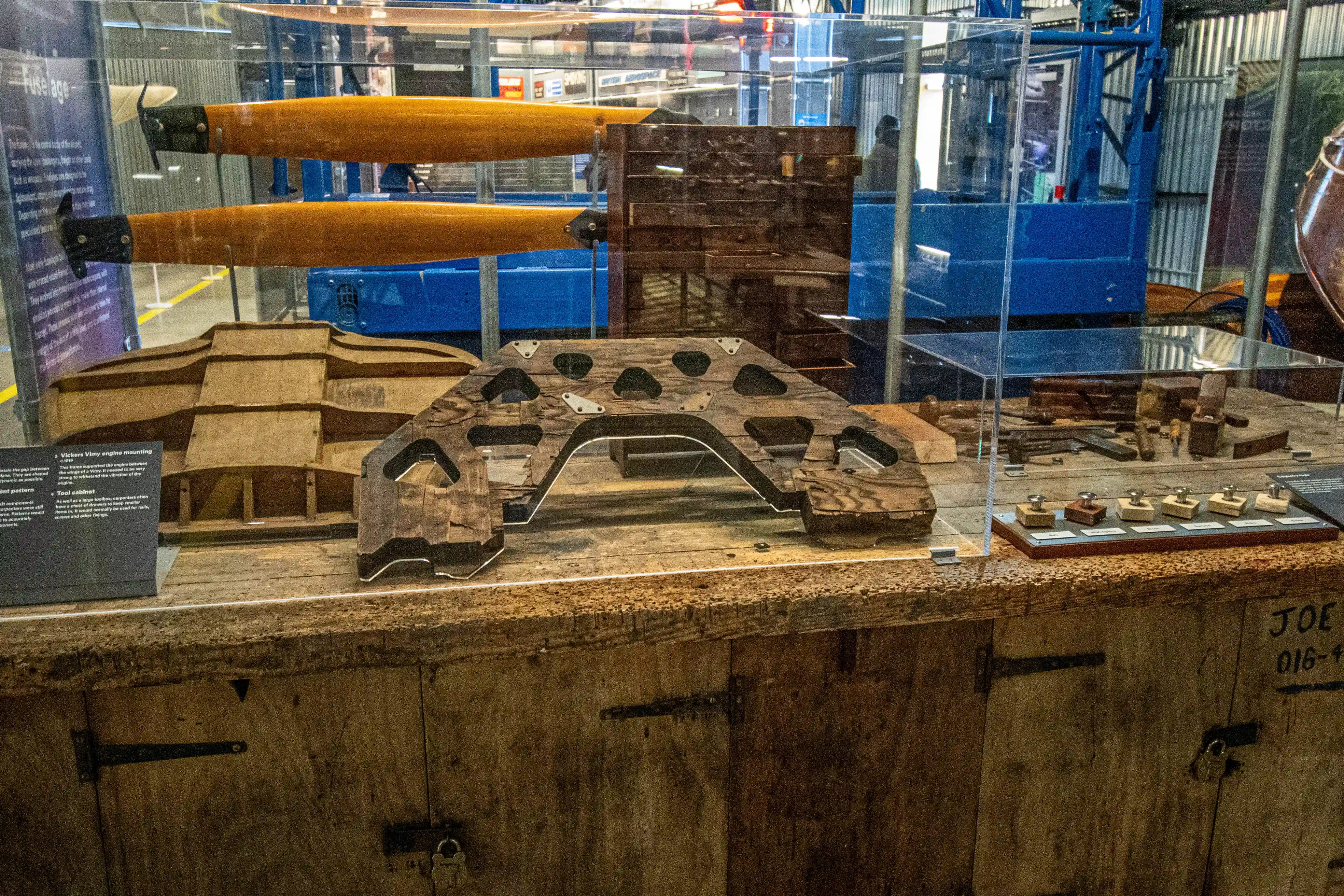 Museum display case containing wooden aircraft propeller blades, tooling forms and manufacturing jigs.