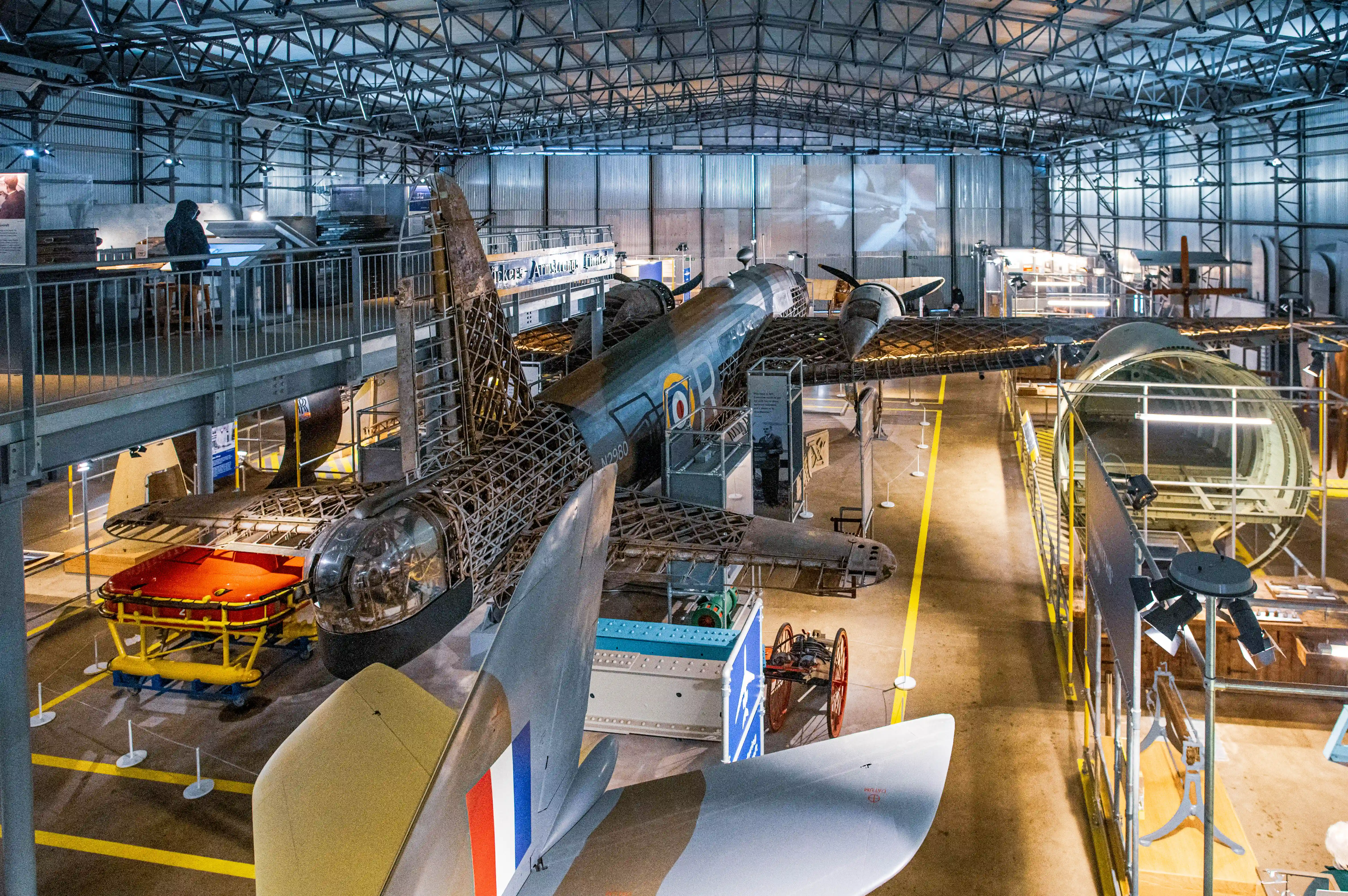Interior view of an aviation museum with several aircraft, including a partially exposed bomber, on display.