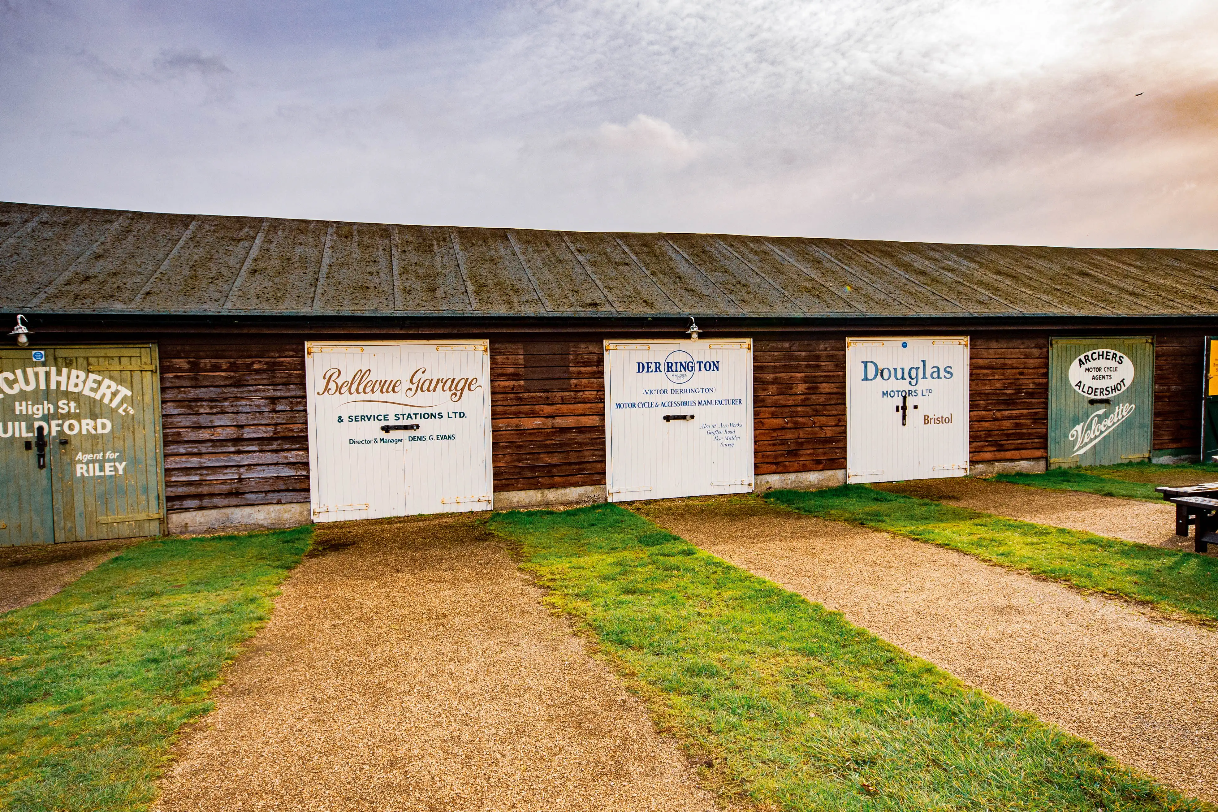 A row of vintage wooden garage doors with retro advertising signage, including 