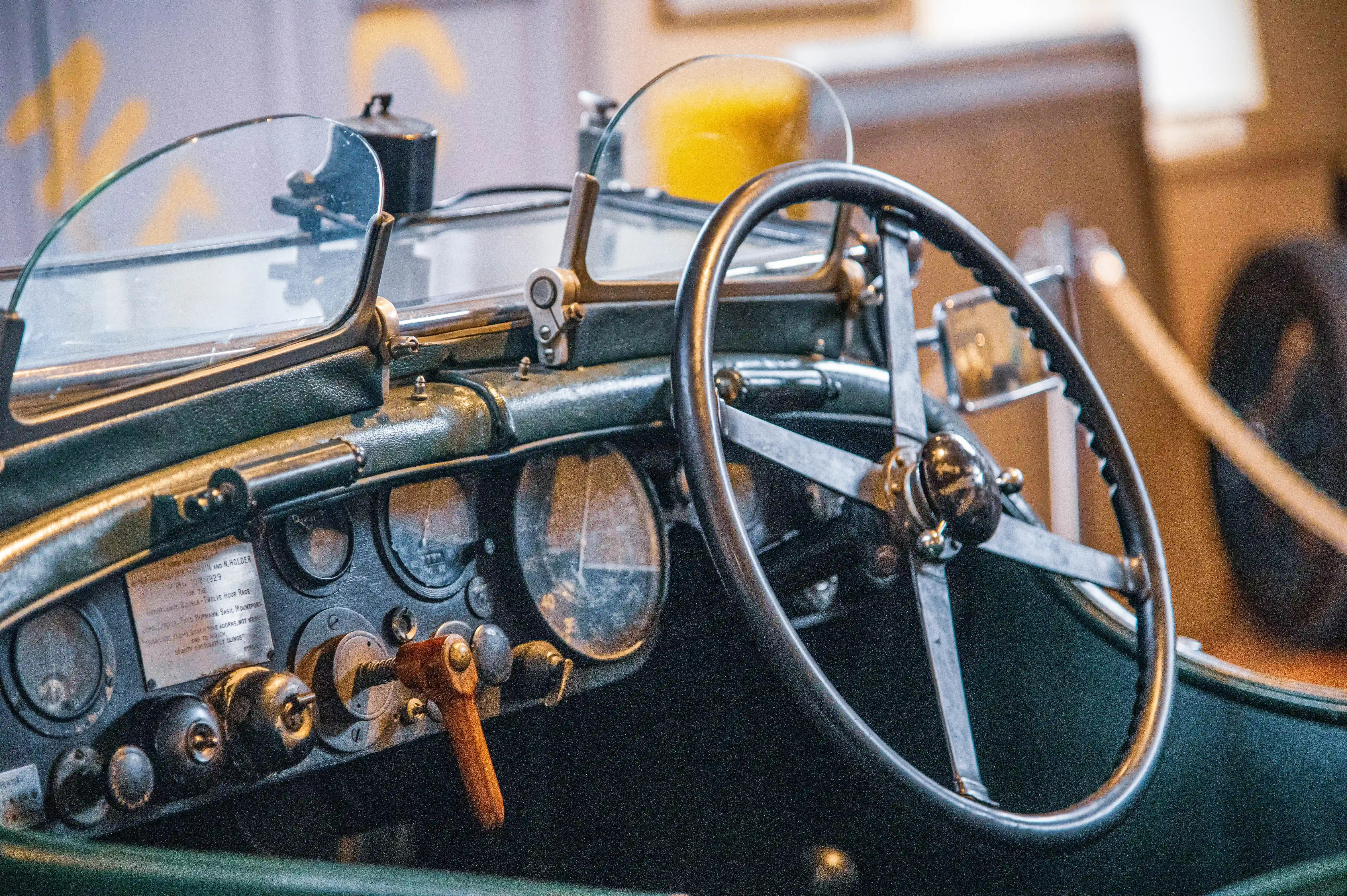 A detailed shot of the dashboard and steering wheel of a classic motor car, highlighting the instrument panel with multiple dials and a prominent steering wheel.