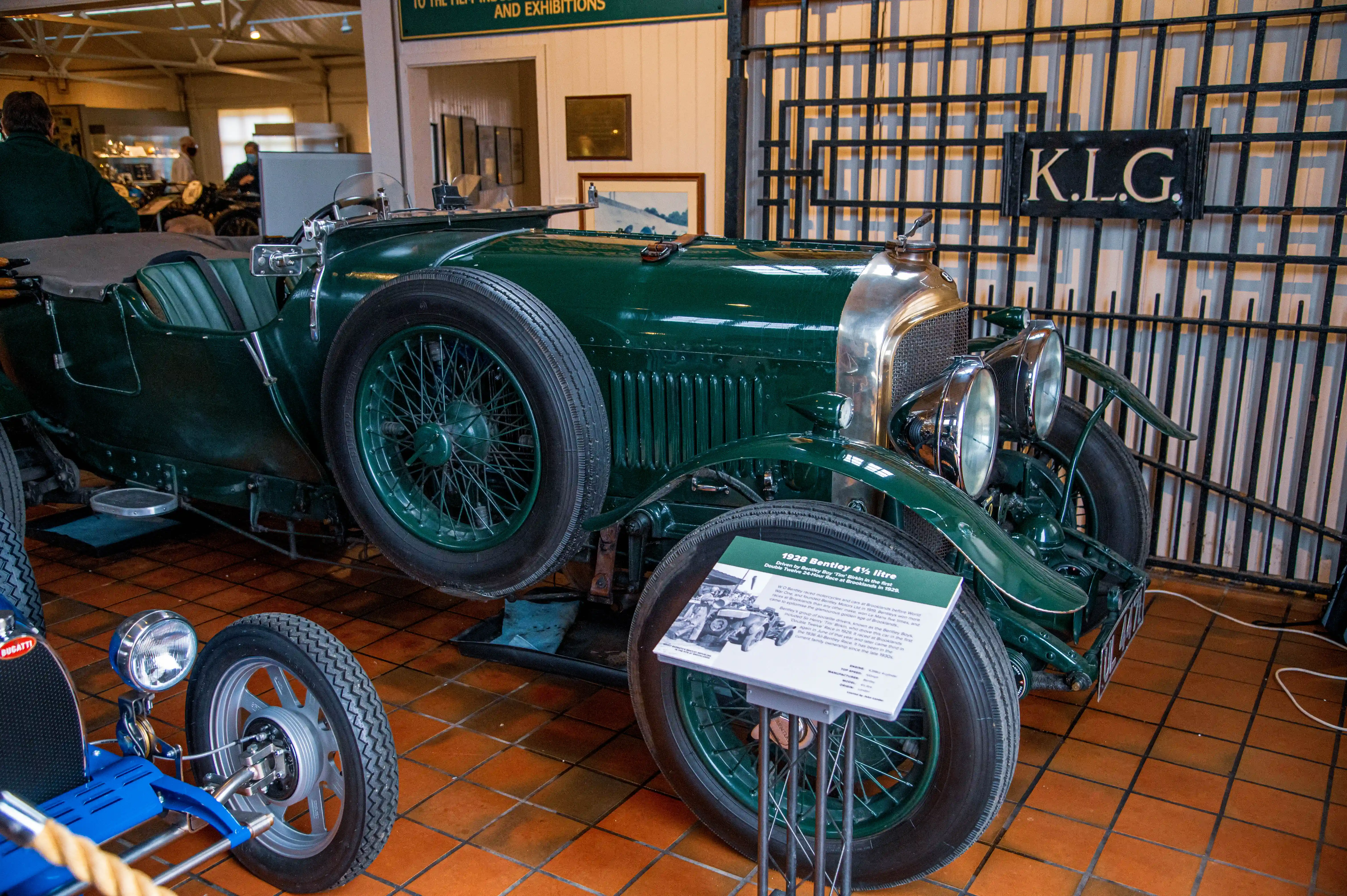 A close-up view of a vintage green Bentley 4½ litre car, featuring its iconic grille, headlamps, and spoked wheels, with a descriptive plaque in front.