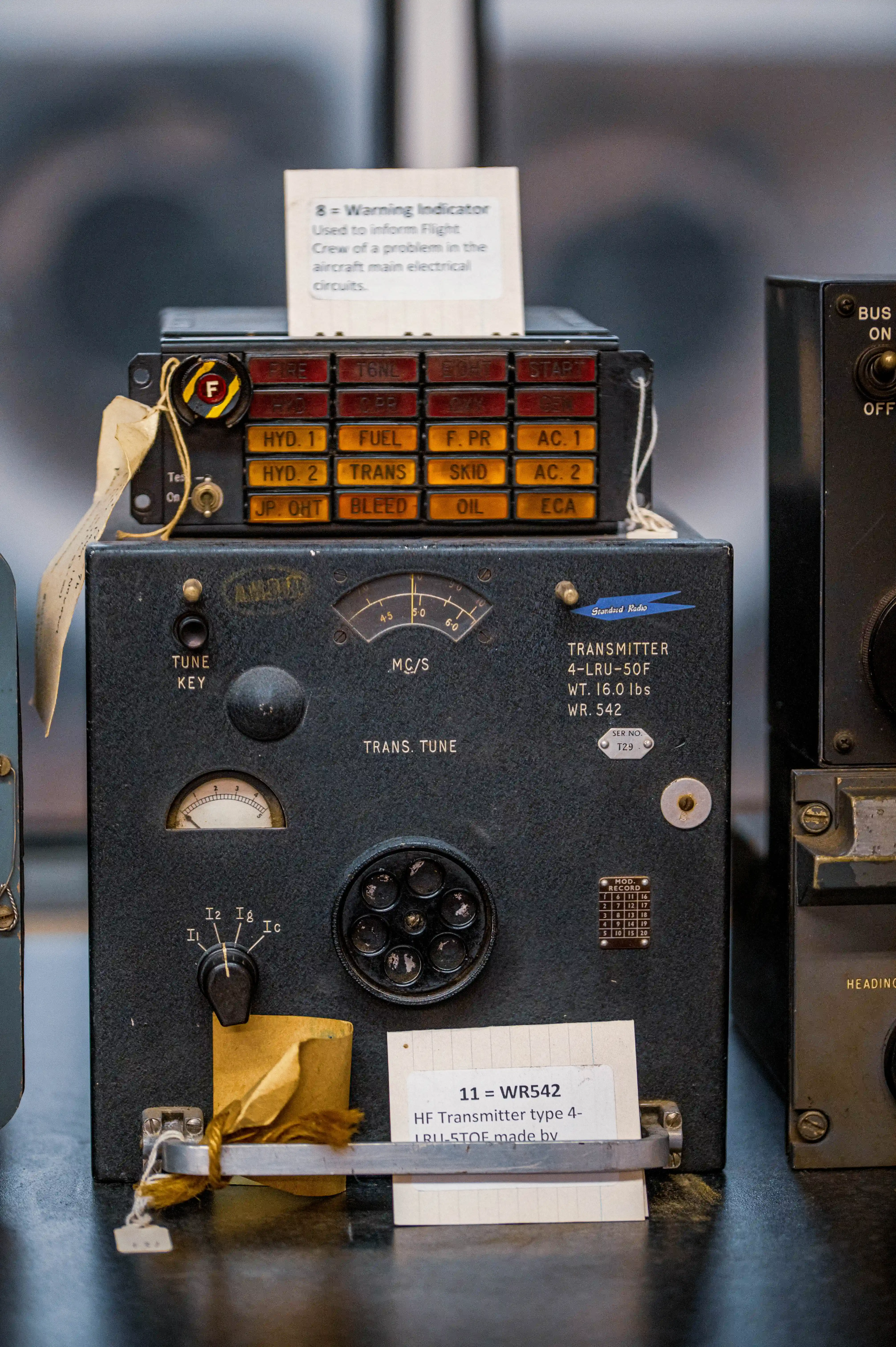 A detailed shot of vintage aircraft electrical warning indicators and an HF transmitter, showing multiple labels and dials on the devices.