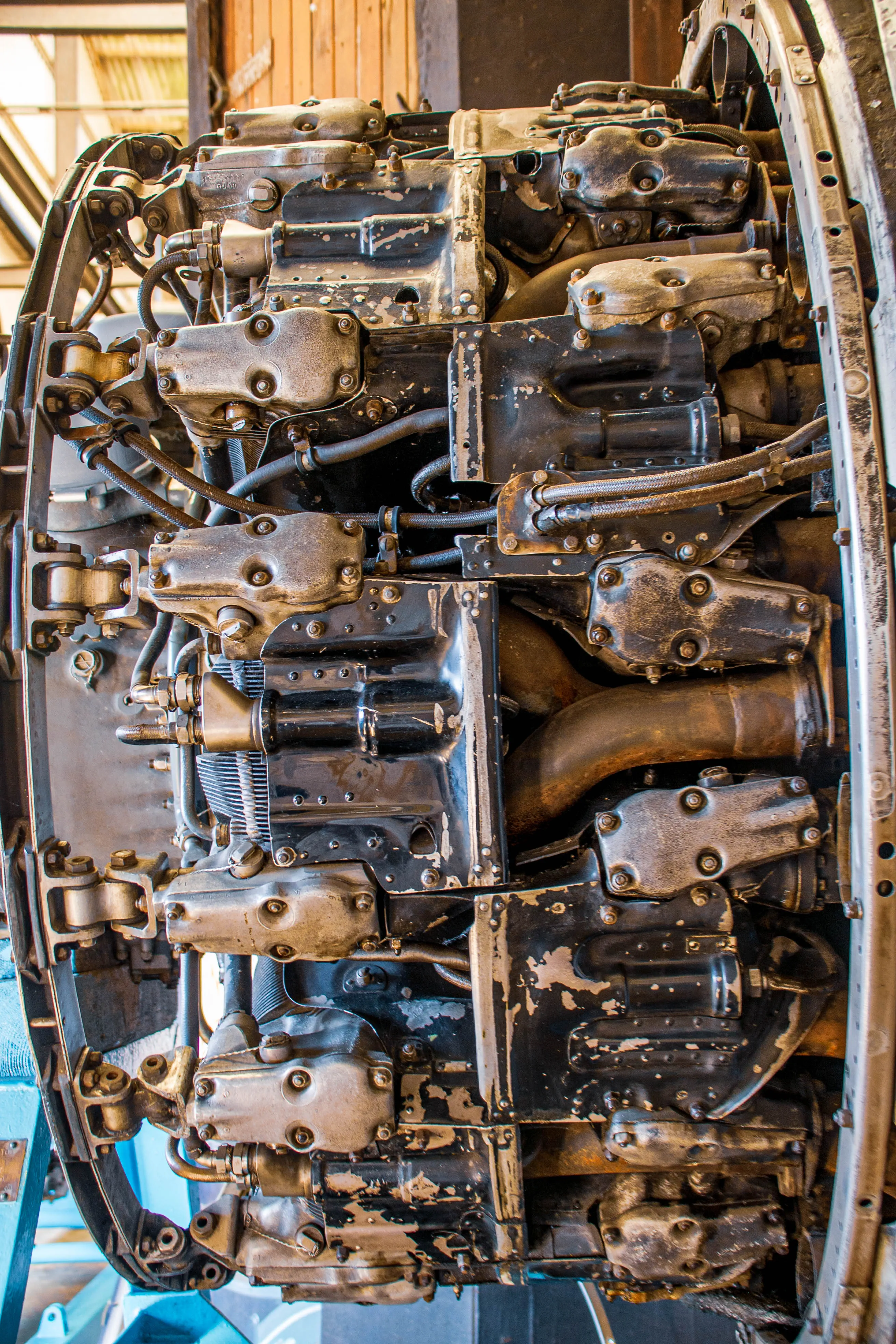 Close-up view of a vintage aircraft engine's internal components, featuring a complex arrangement of metal cylinders, pipes, and fasteners, with visible wear and tear.