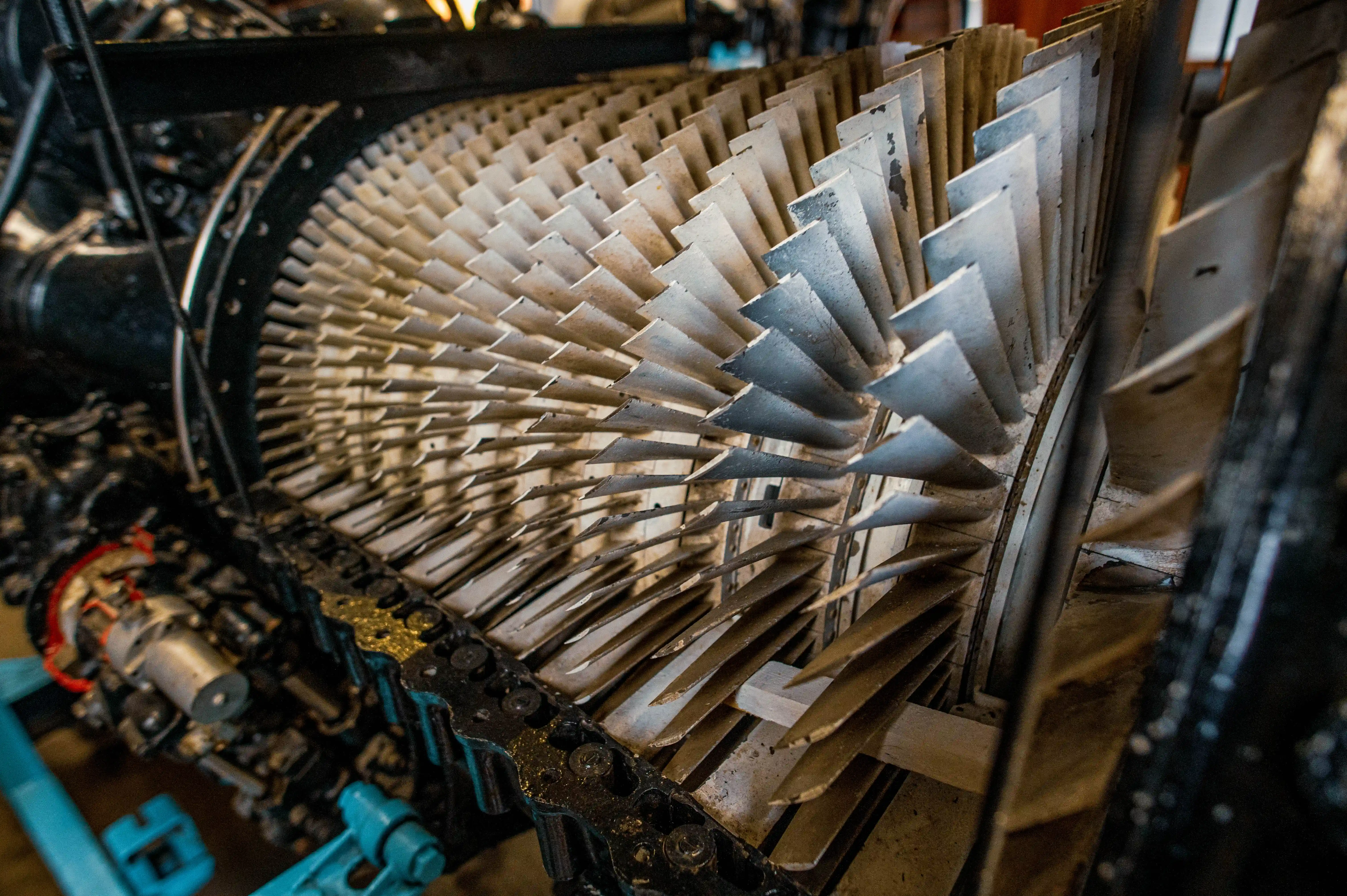 Close-up of the metallic turbine blades of a jet engine, showcasing their layered, radial arrangement and signs of use.